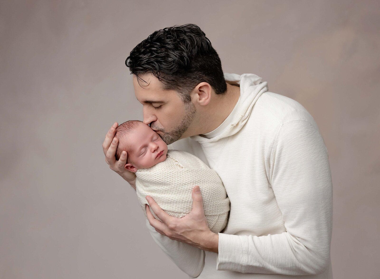 Dad holding newborn baby boy and kissing his head lovingly. Photo by Jenni Nikki Photography, Marietta Newborn photographer.