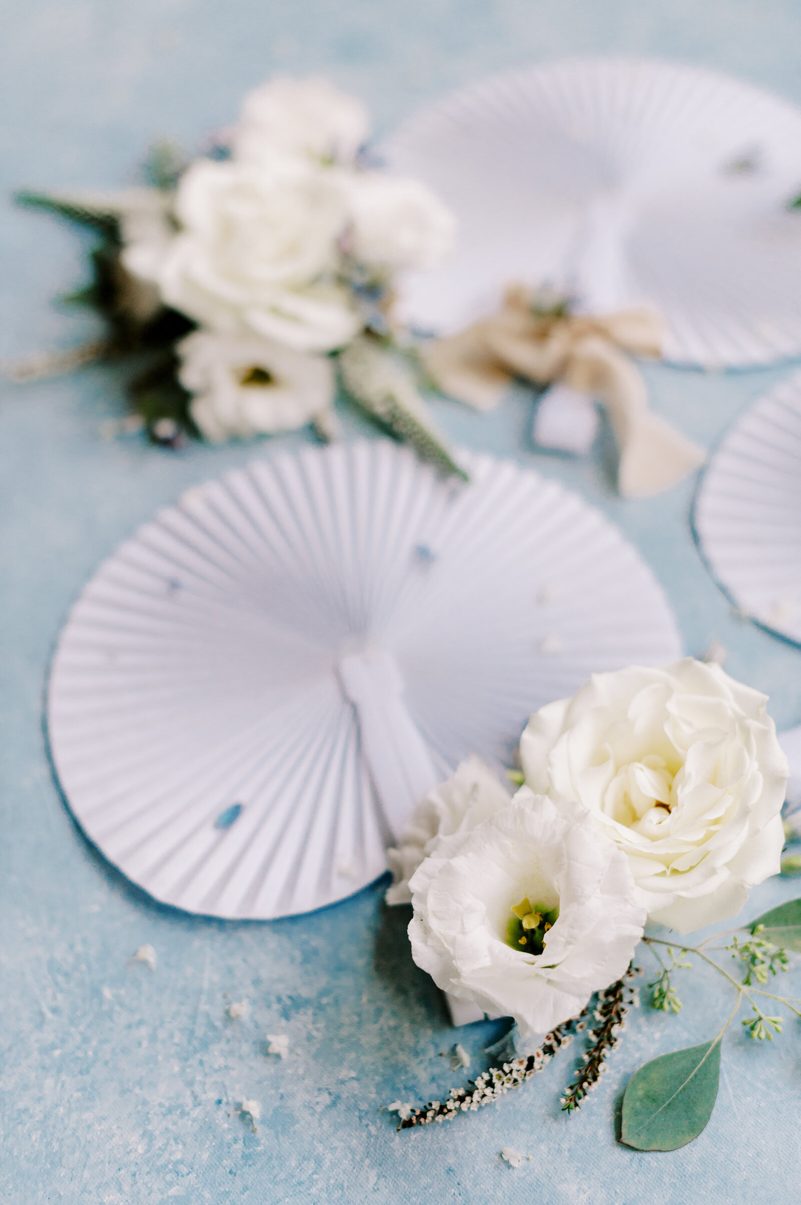 Blue wedding flat lay with fans, white flowers, and hand painted rollable canvas styling mat taken by the Best Boise Wedding Photographers