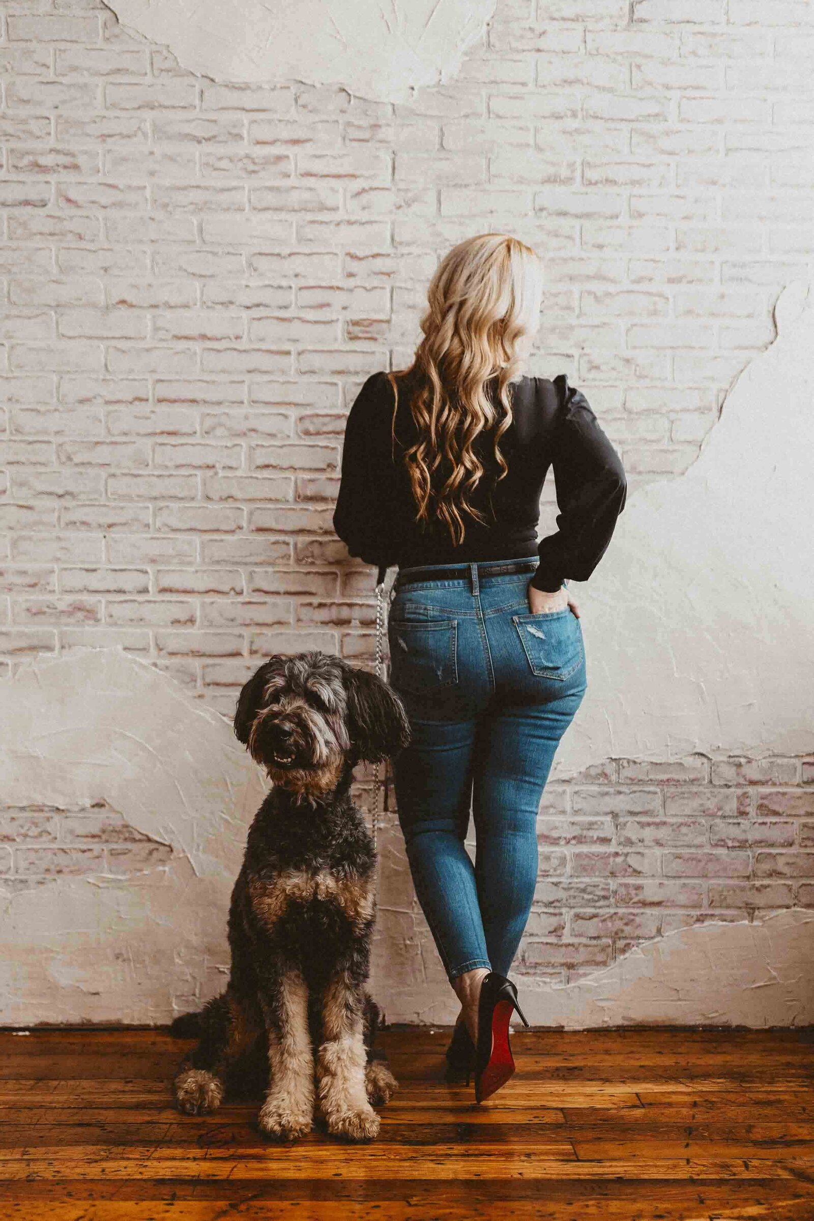 woman facing on the wall while her dog facing in front