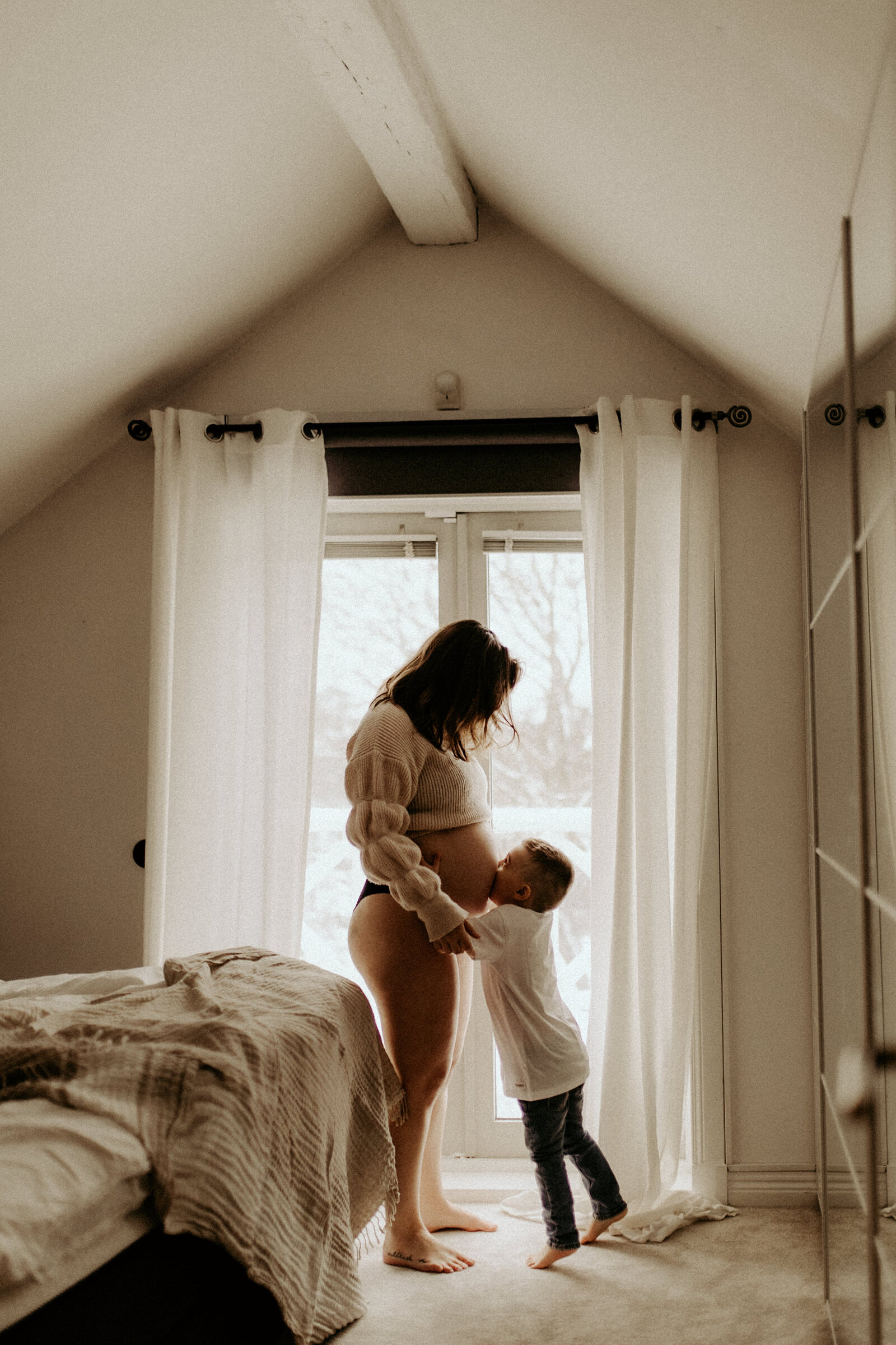en mamma får en puss på sin gravidmage av sin son