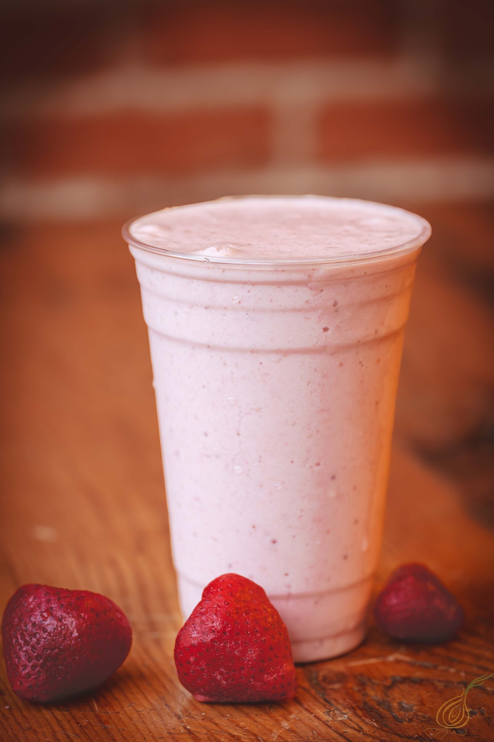 A refreshing strawberry smoothie topped and fresh strawberries on the side, served in a clear glass.