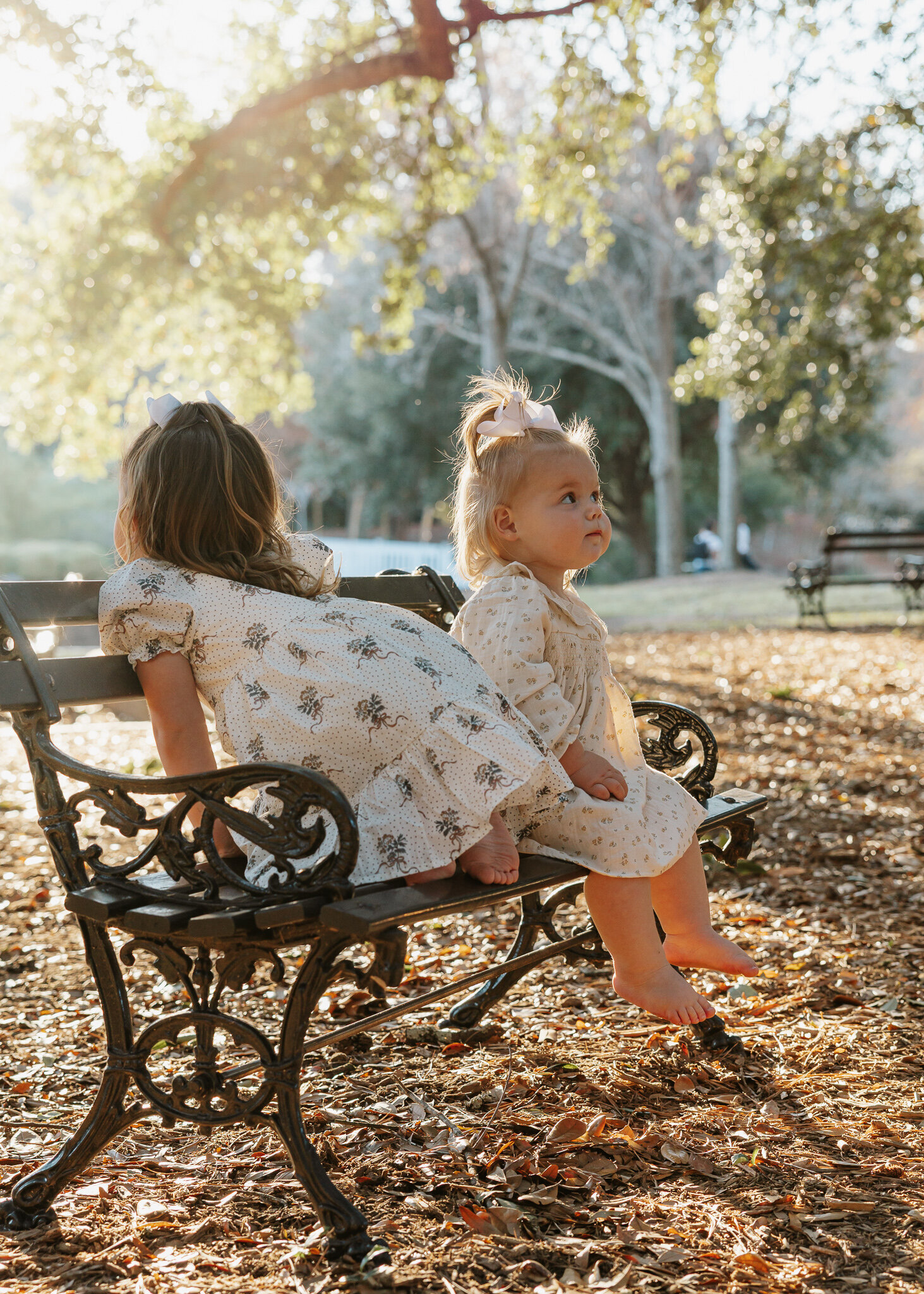 Two young siblings sitting together on a bench during a family session at Hopelands Gardens in Aiken SC.