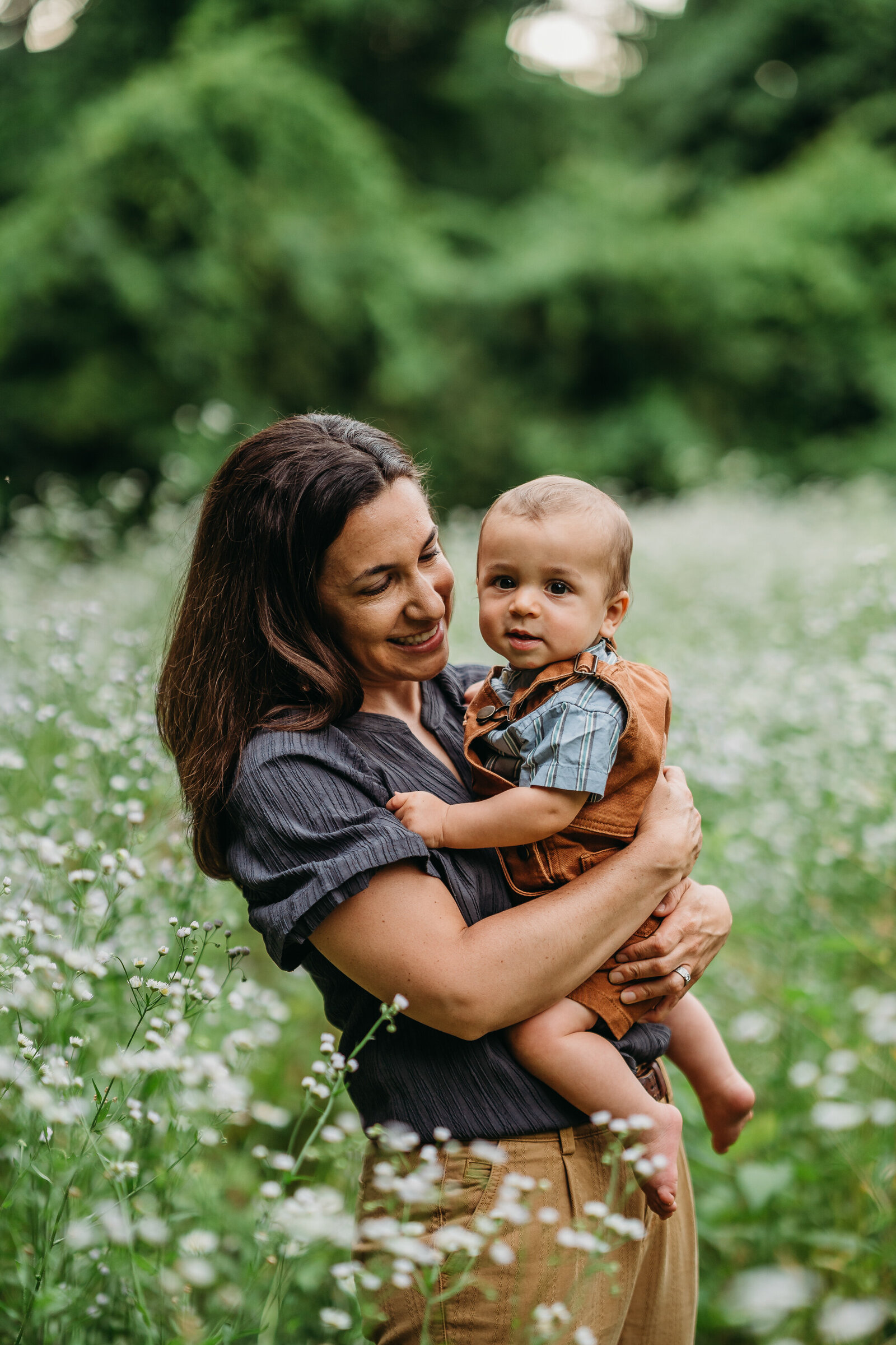 mother holds baby boy in field of white flowers