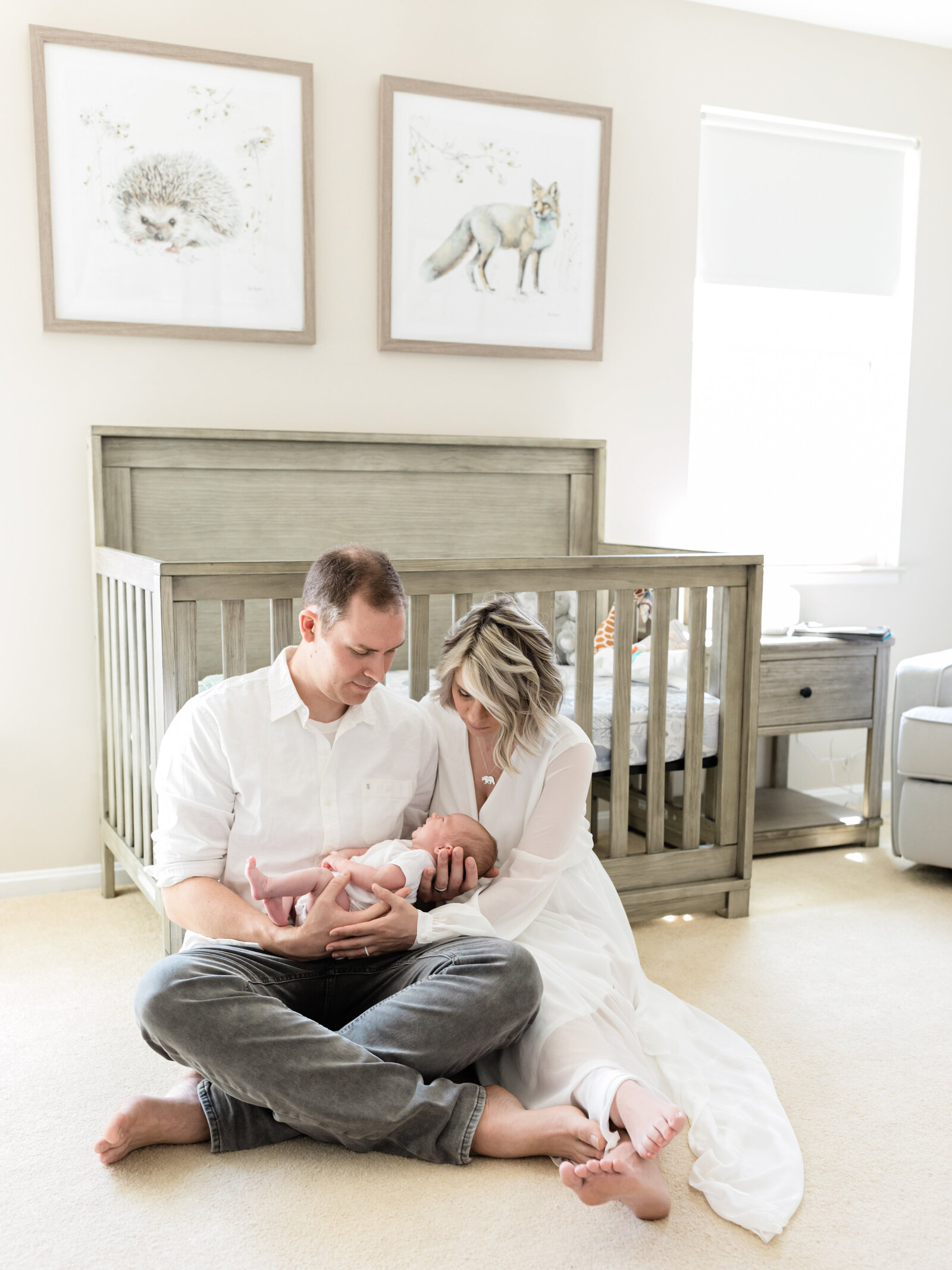 mom and dad holding newborn baby girl in nursery for in home photoshoot