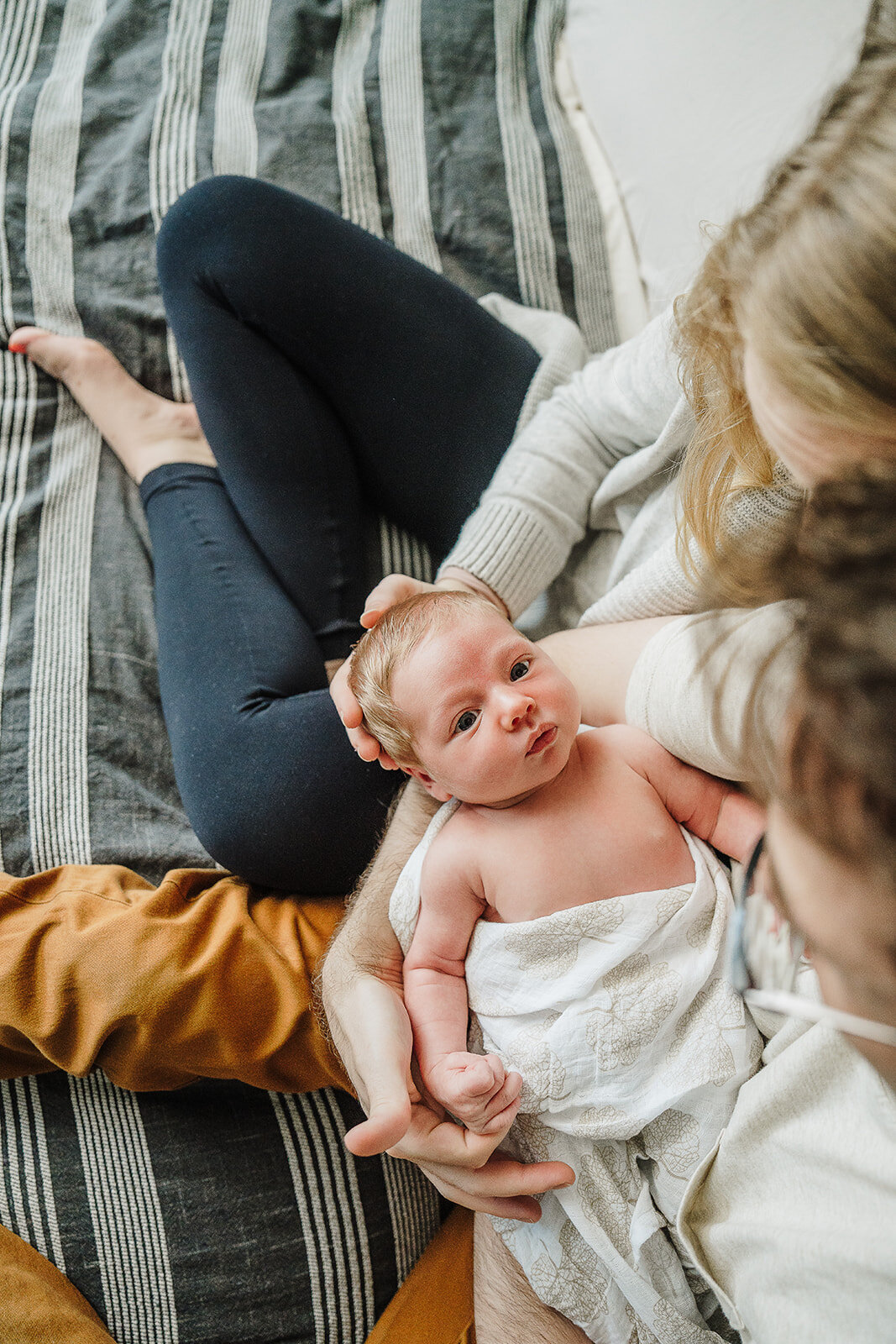 newborn baby looks up at parents on bed