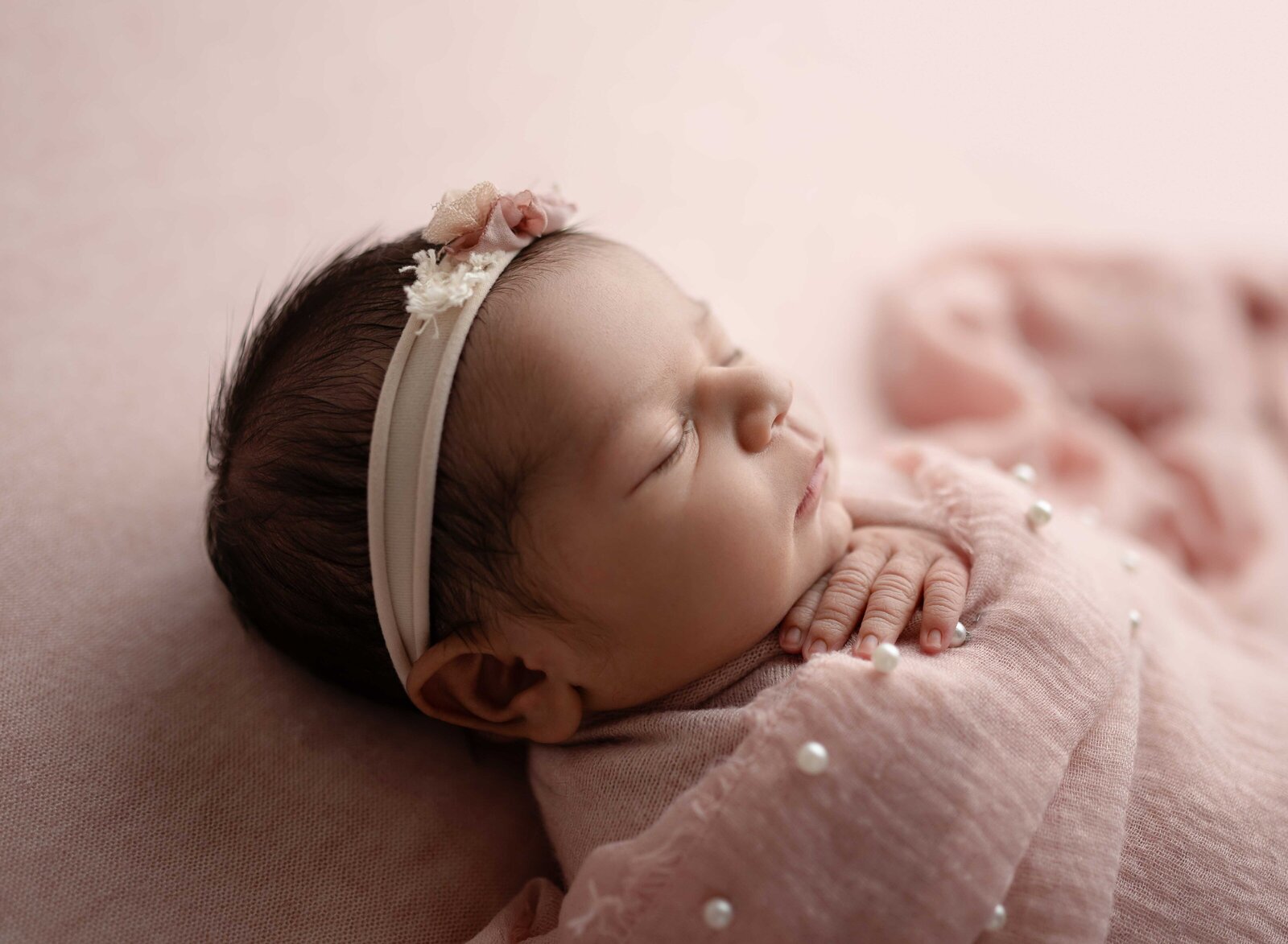 Baby girl sleeping with pearl blanket and back lighting. Photographed at Atlanta Baby photo studio.