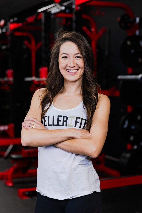 Woman folds arms in front of squat machines for her companies headshots.