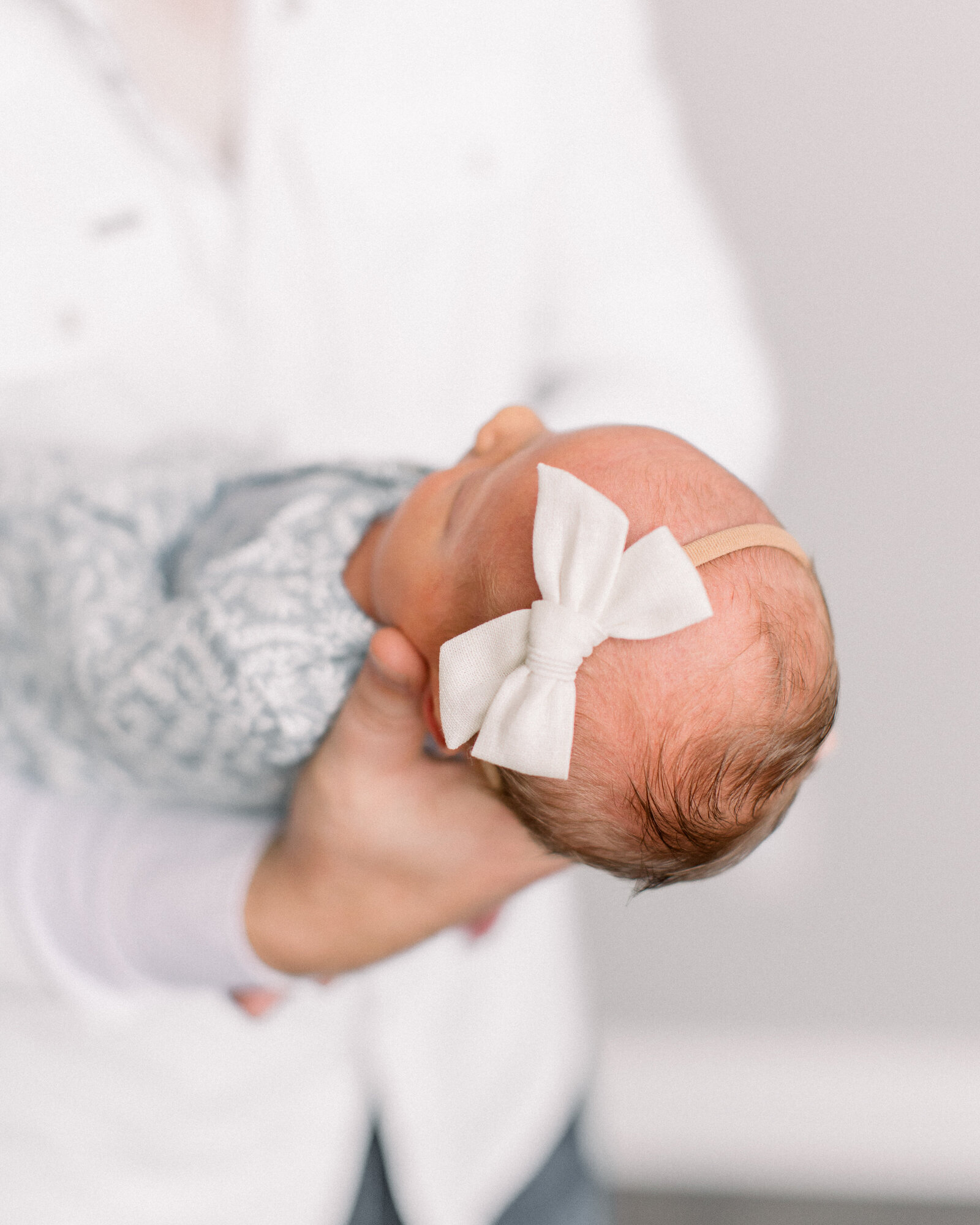 Dad holds baby girl in front of him by NH newborn photographer Fieldstone Studio.