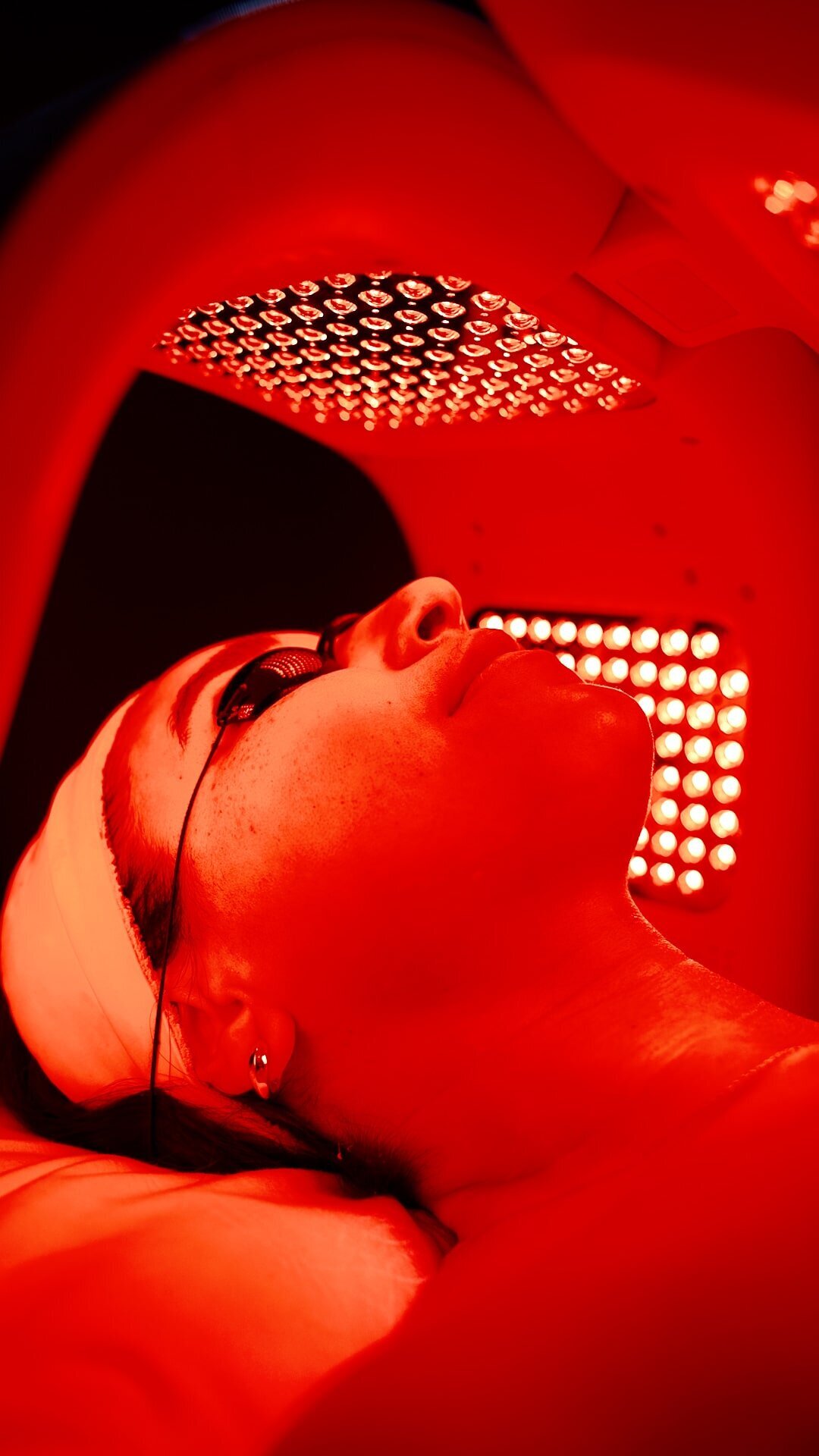 Patient lying under a red light therapy panel