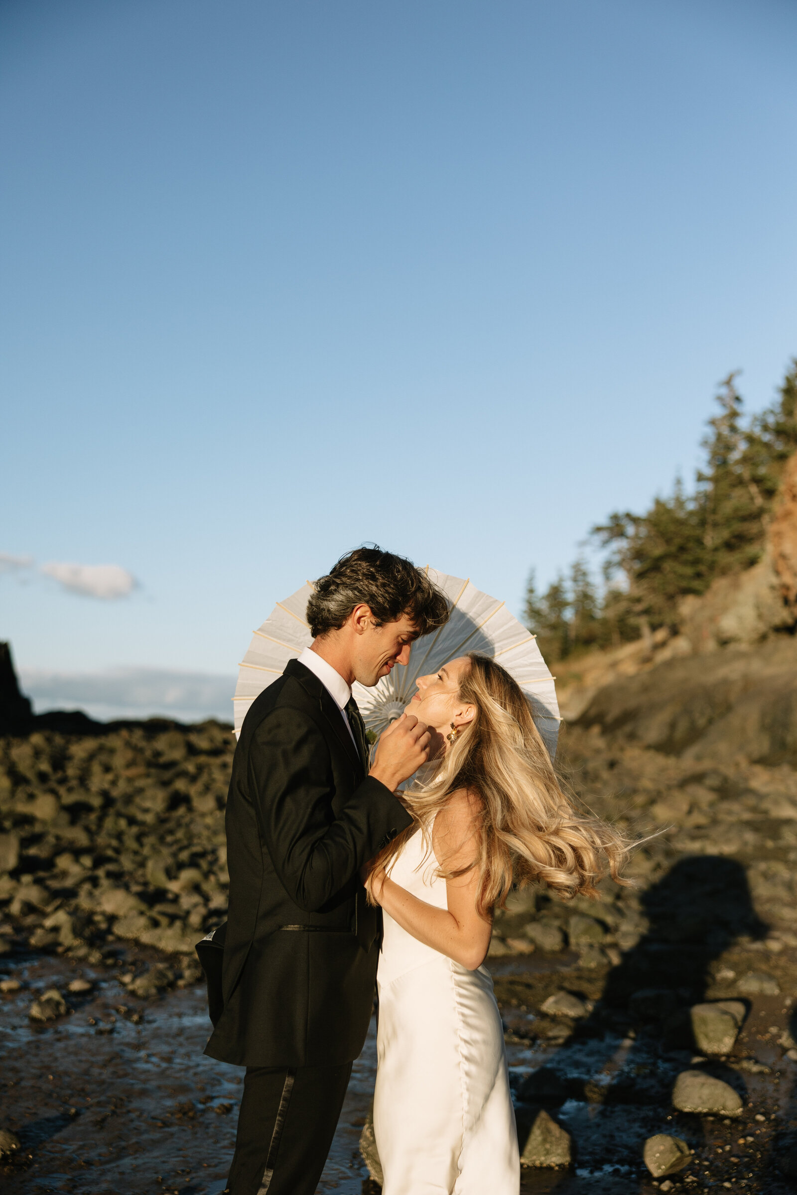 A bride and groom pose for beach wedding portraits at sunset on a Nova Scotia beach.