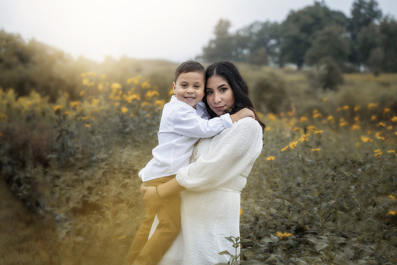 Mom holding her son in front of grass with yellow flowers