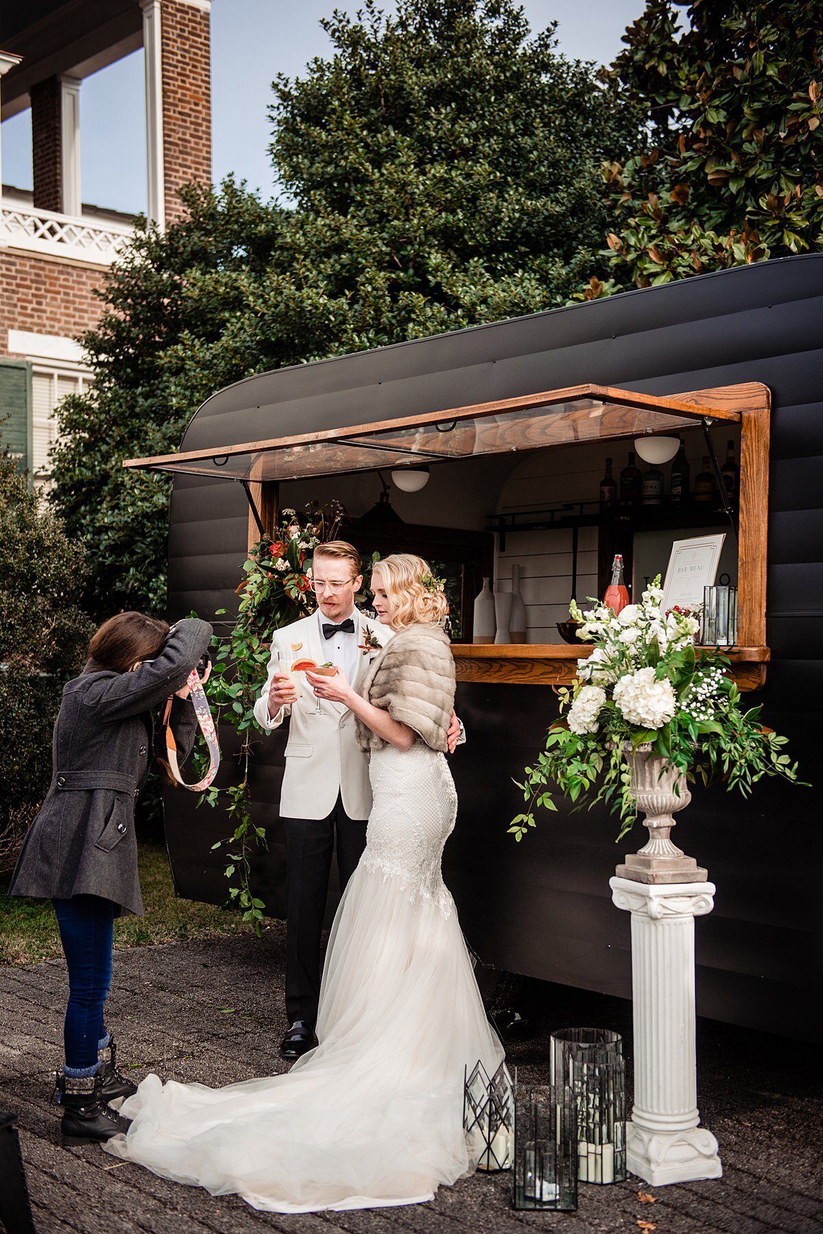 Photo of photographer taking photo of bride and groom getting cocktails at their mobile bar rental