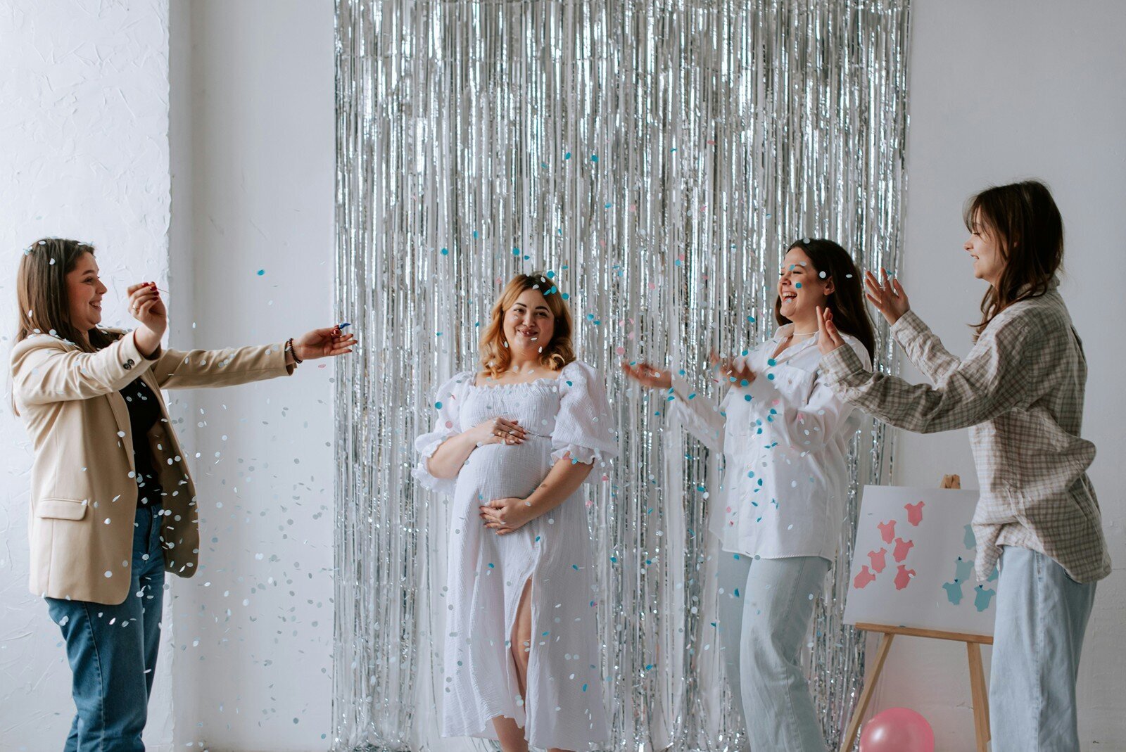Baby shower gender reveal with guests tossing confetti over expecting mom