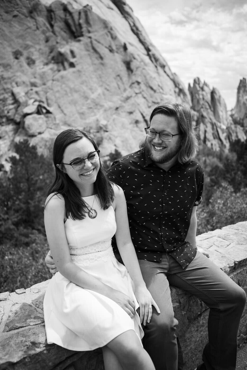 A couple sits together in front of red rock formations.