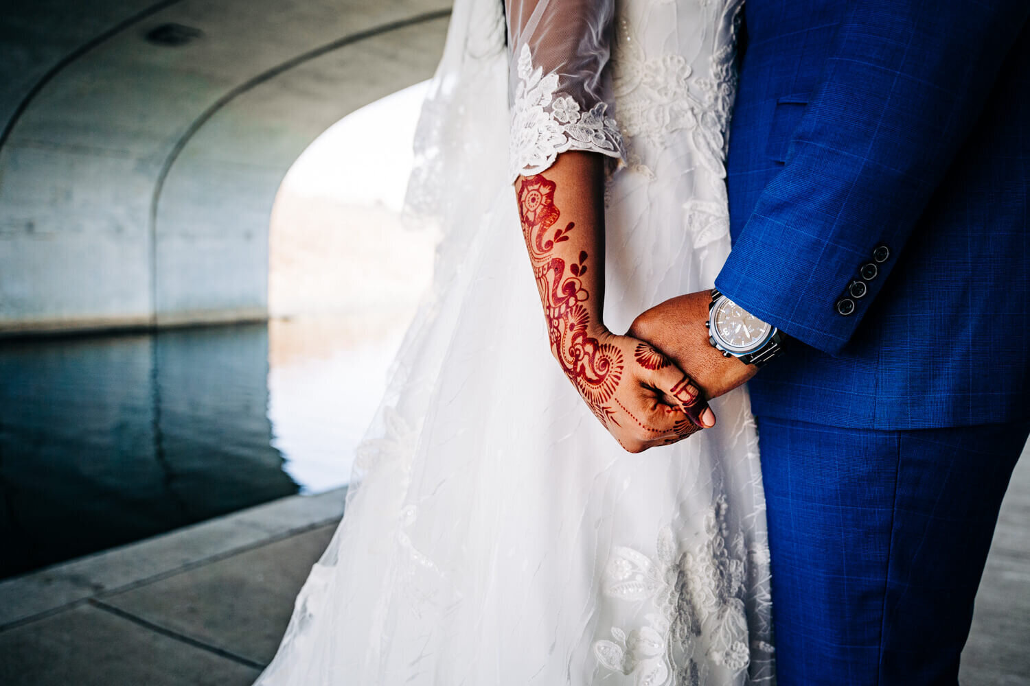 Standing beside a river, an Indian wedding couple holds hands in Indianapolis, Indiana.