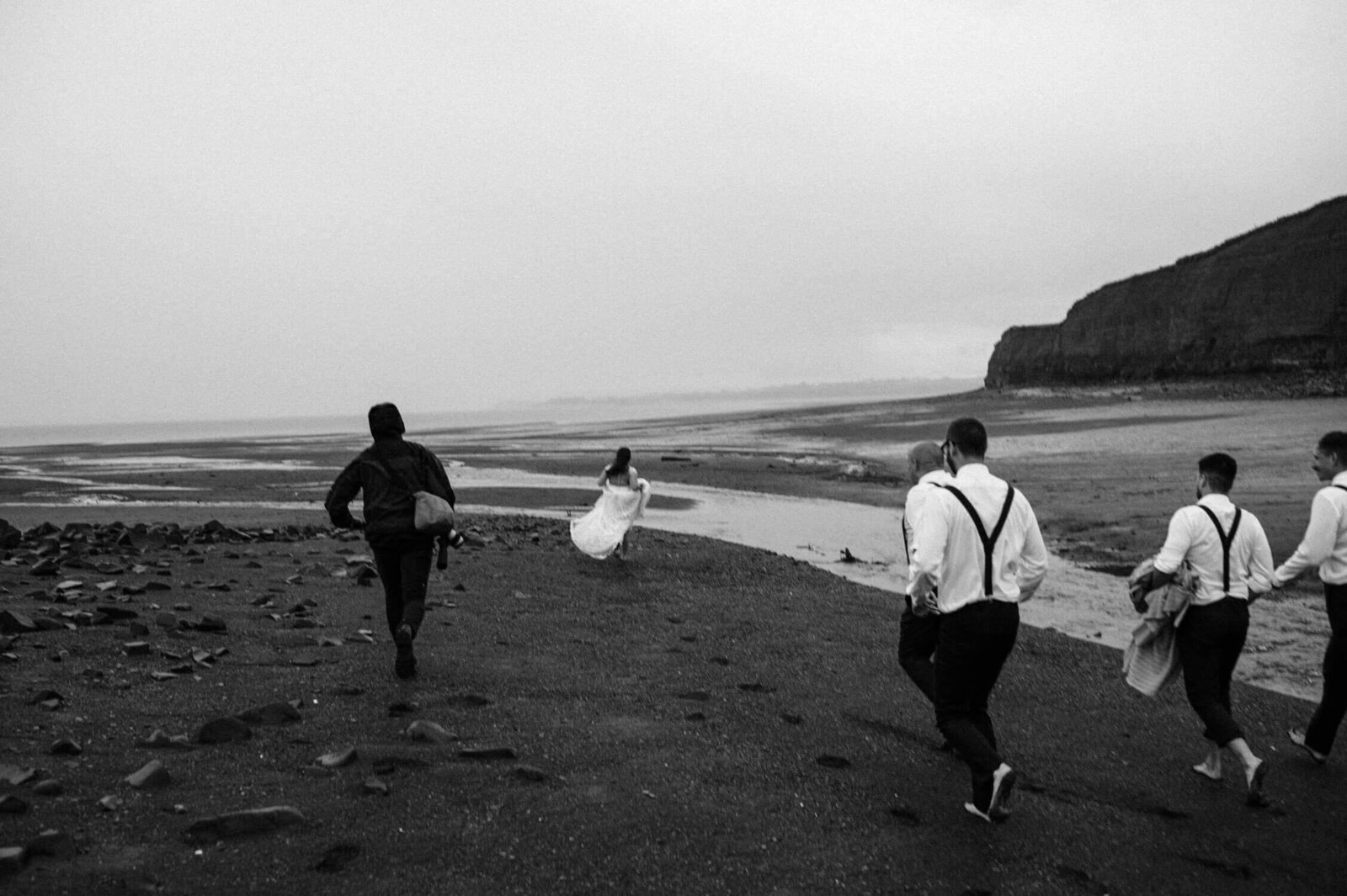 Wedding party running down the beach at low tide in Cape Breton.