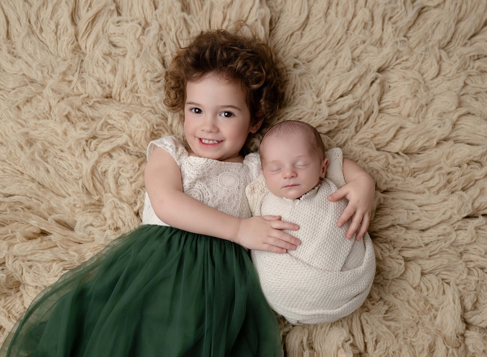 Marietta newborn photo of baby and big sister lying down on fur blanket.