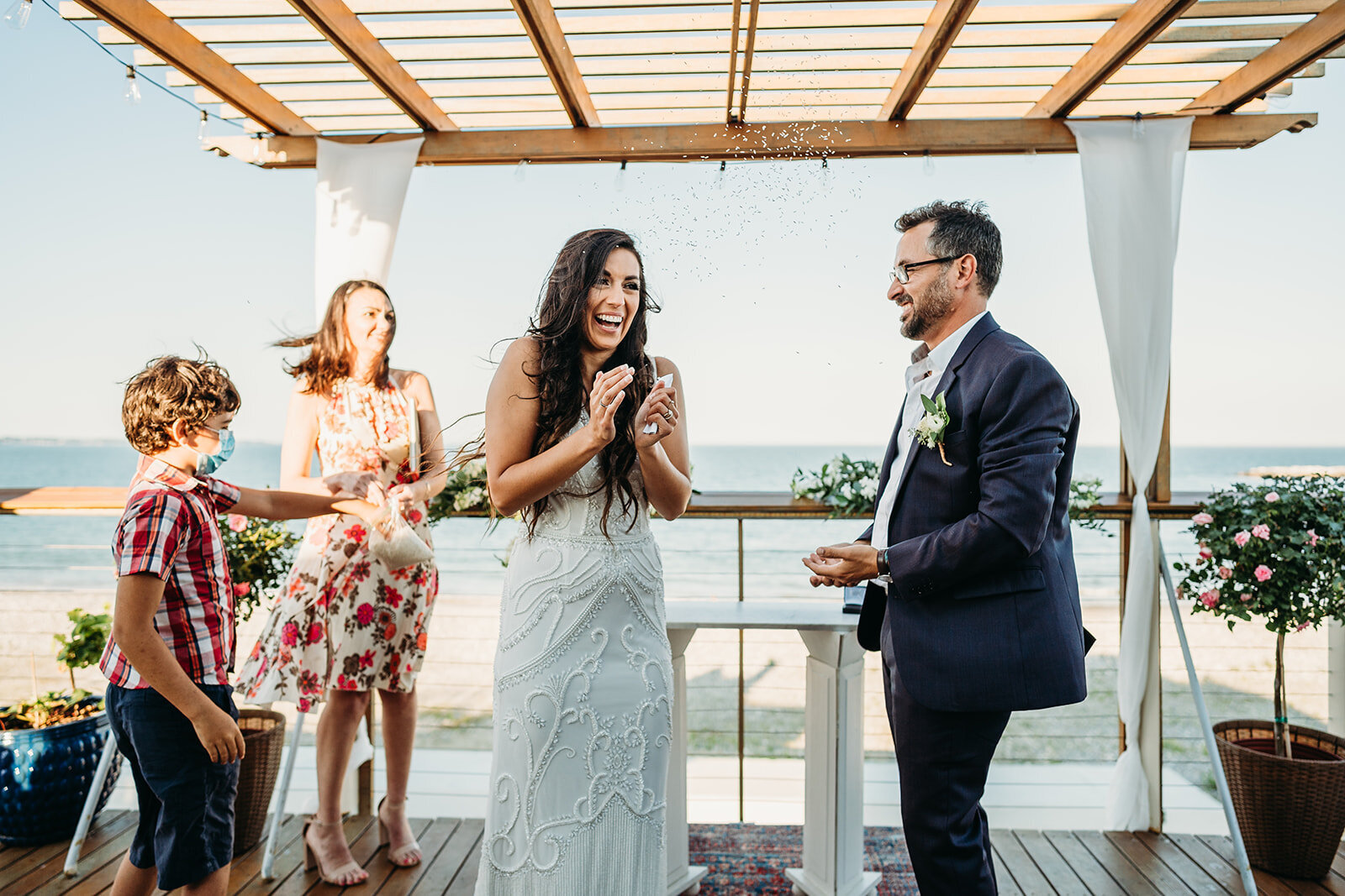bride and groom clap and throw rice at the end of rooftop ceremony