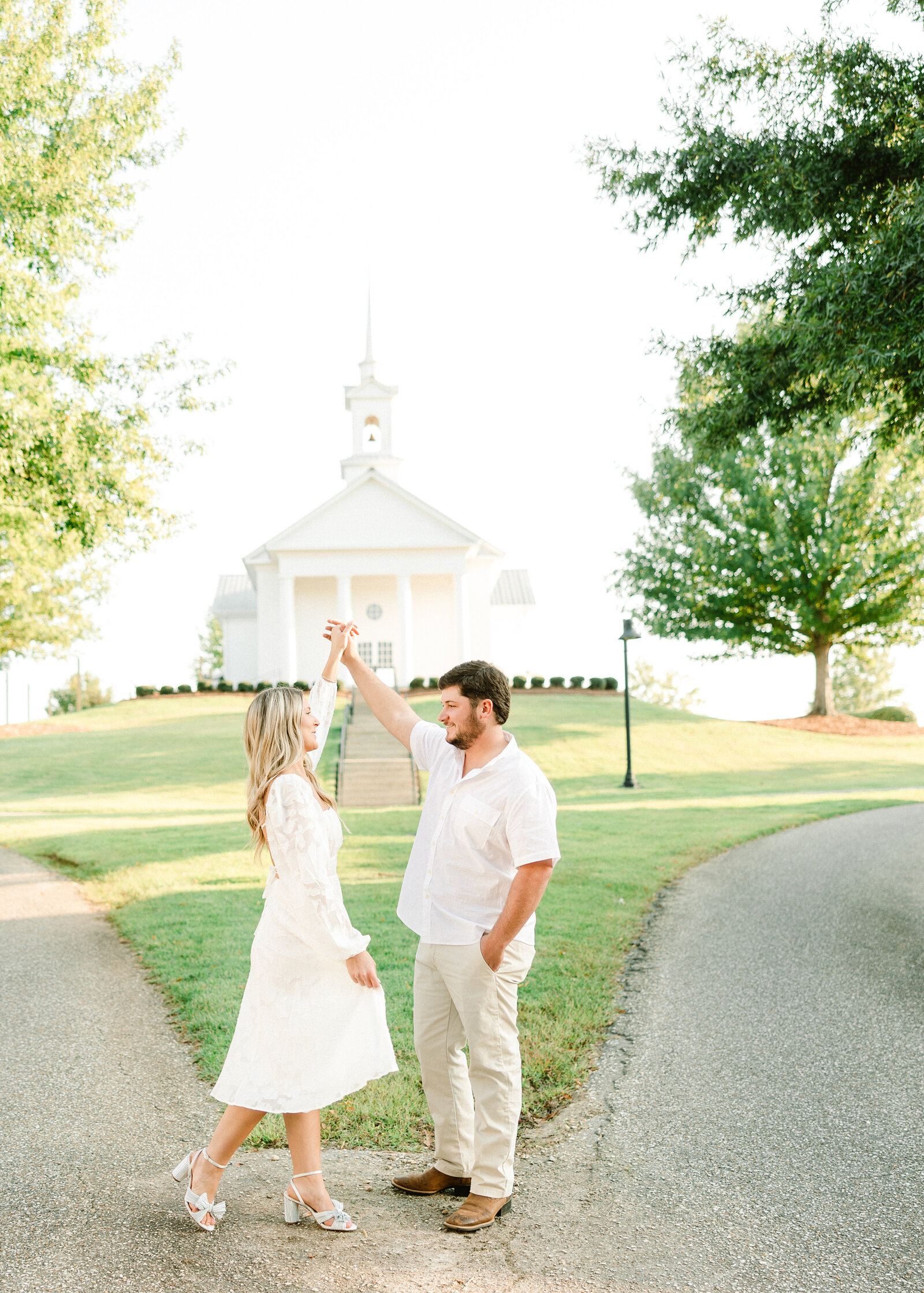 Kelby and Mason embracing by the riverside under a beautiful sunset, photographed by Abby Bell Photography. Personalized and romantic engagement photography in Alabama.