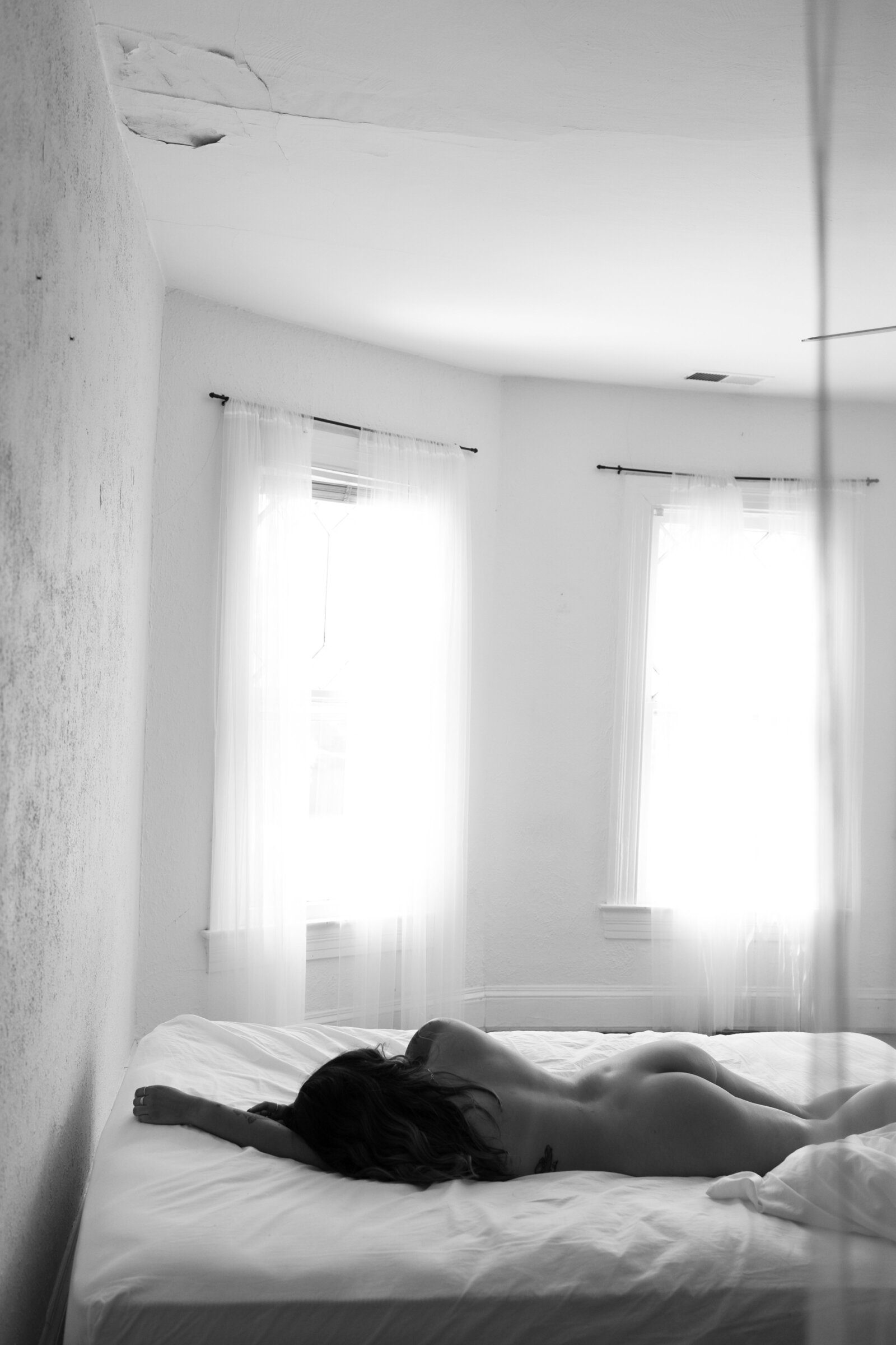 Black and white boudoir photo of woman lying on bed