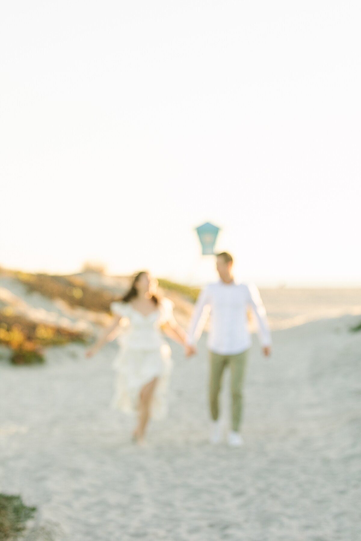 Couple running down a path to the beach in Coronado.