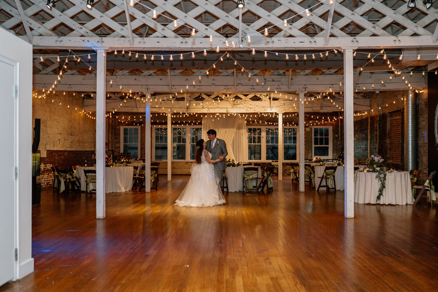 Couple dancing under string lights indoors