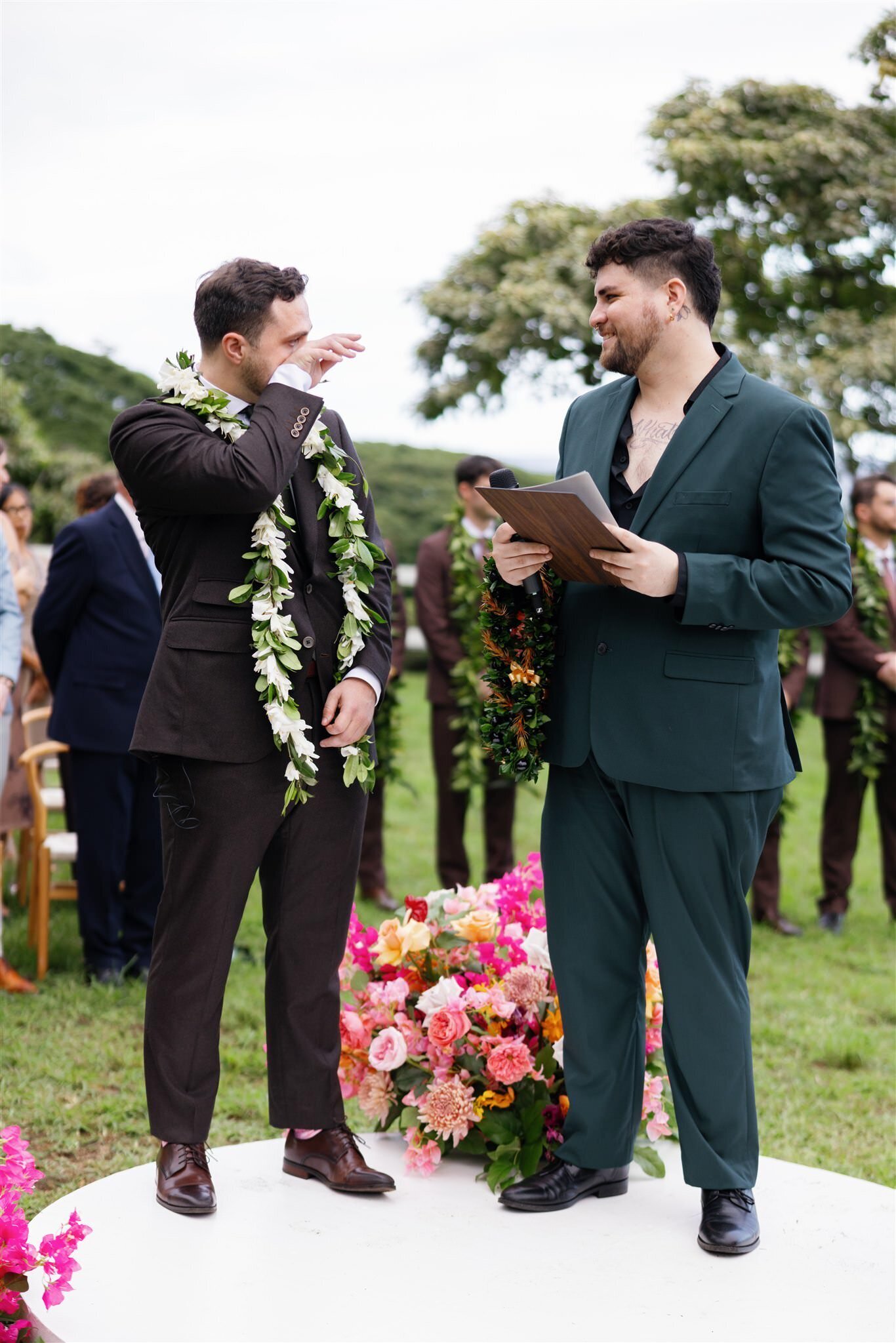A newlywed wiping a tear and talking with their officiant. 
