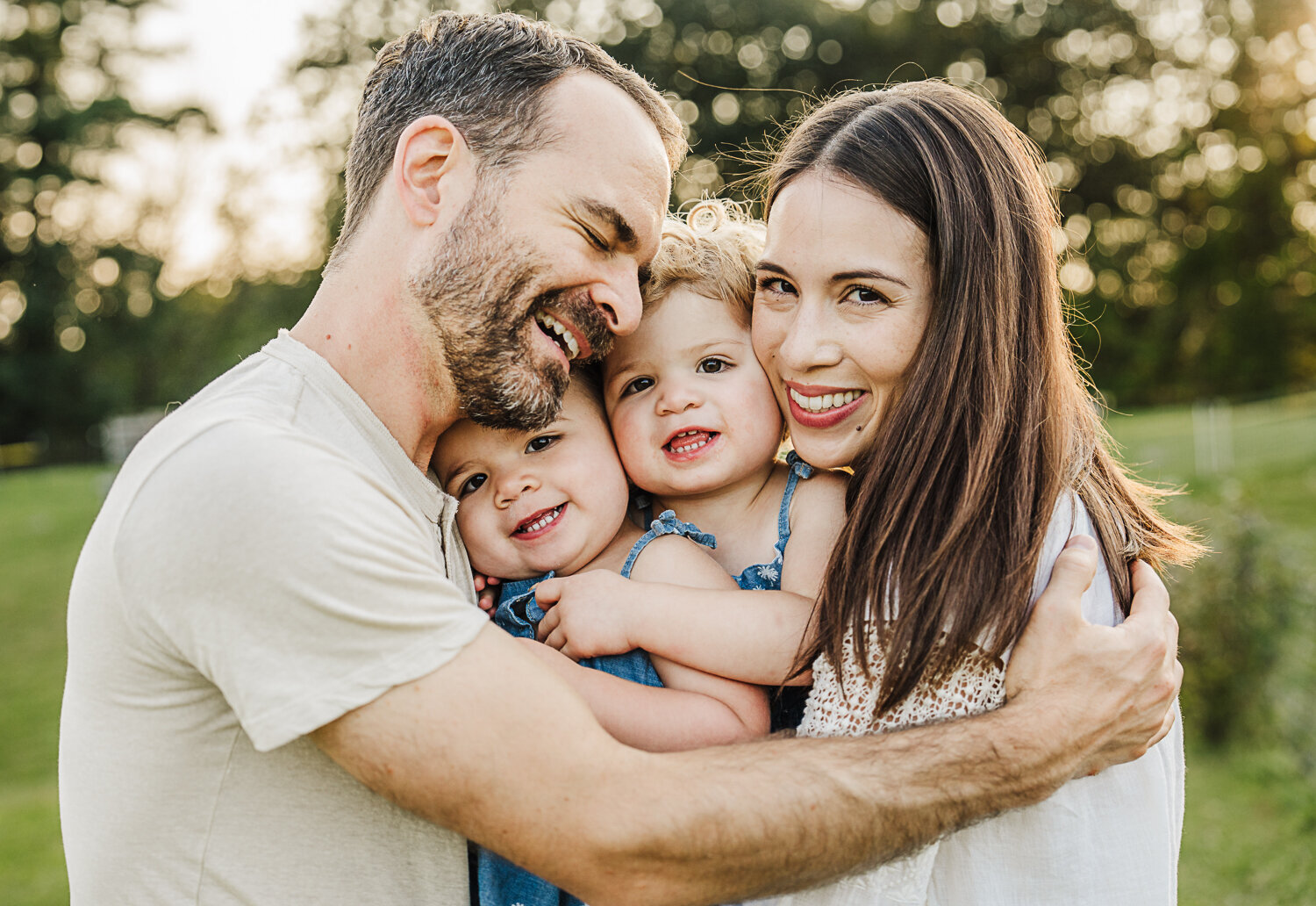 mom and dad hug twin toddler girls for family photos