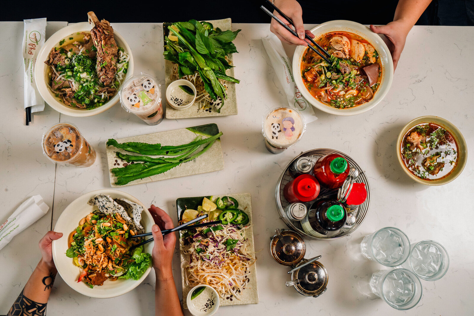 An eclectic selection of traditional Vietnamese dishes on a table, encircled by people immersed in a delightful dining experience