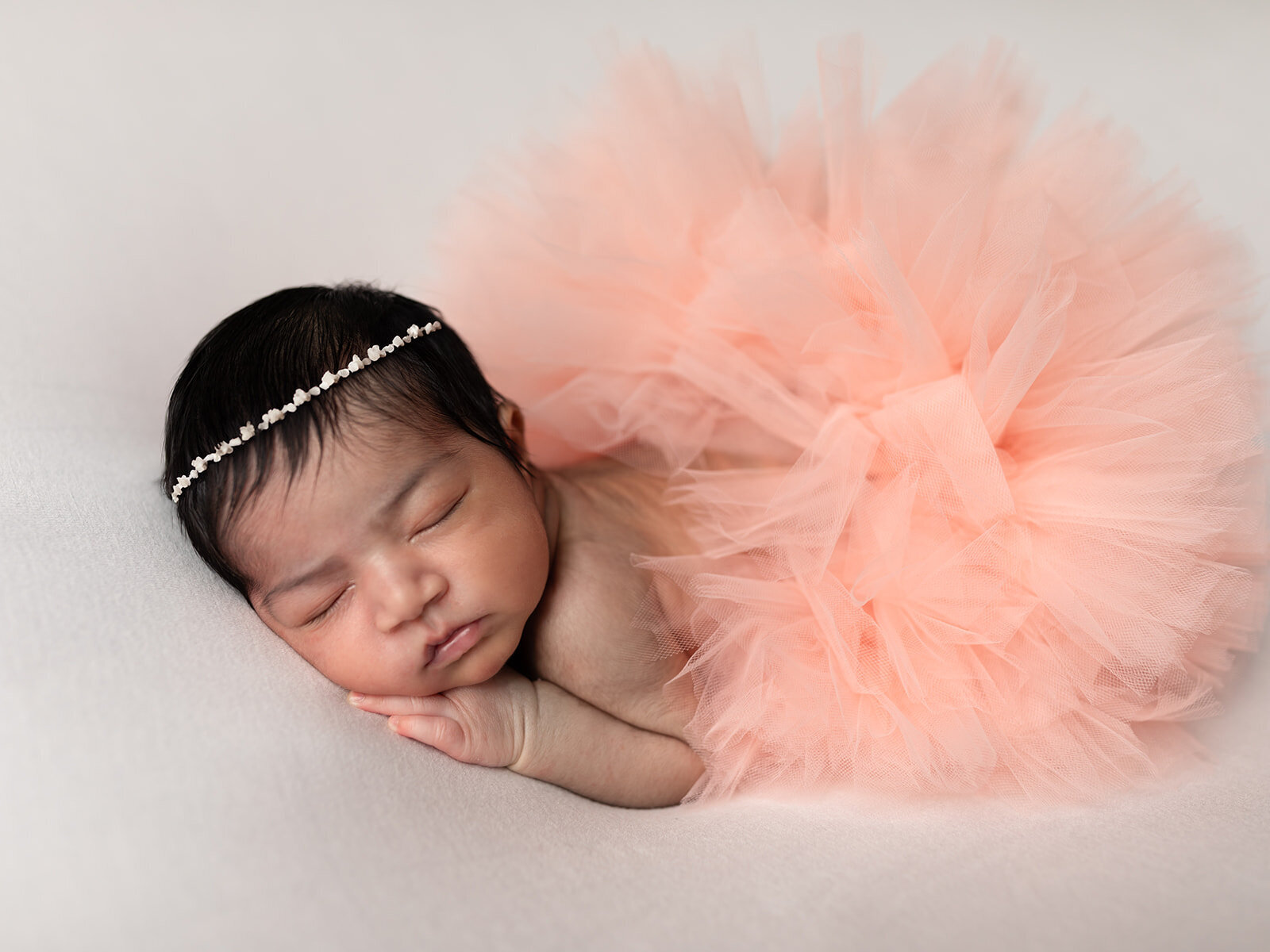 newborn baby girl in pink tutu posed for newborn studio portraits