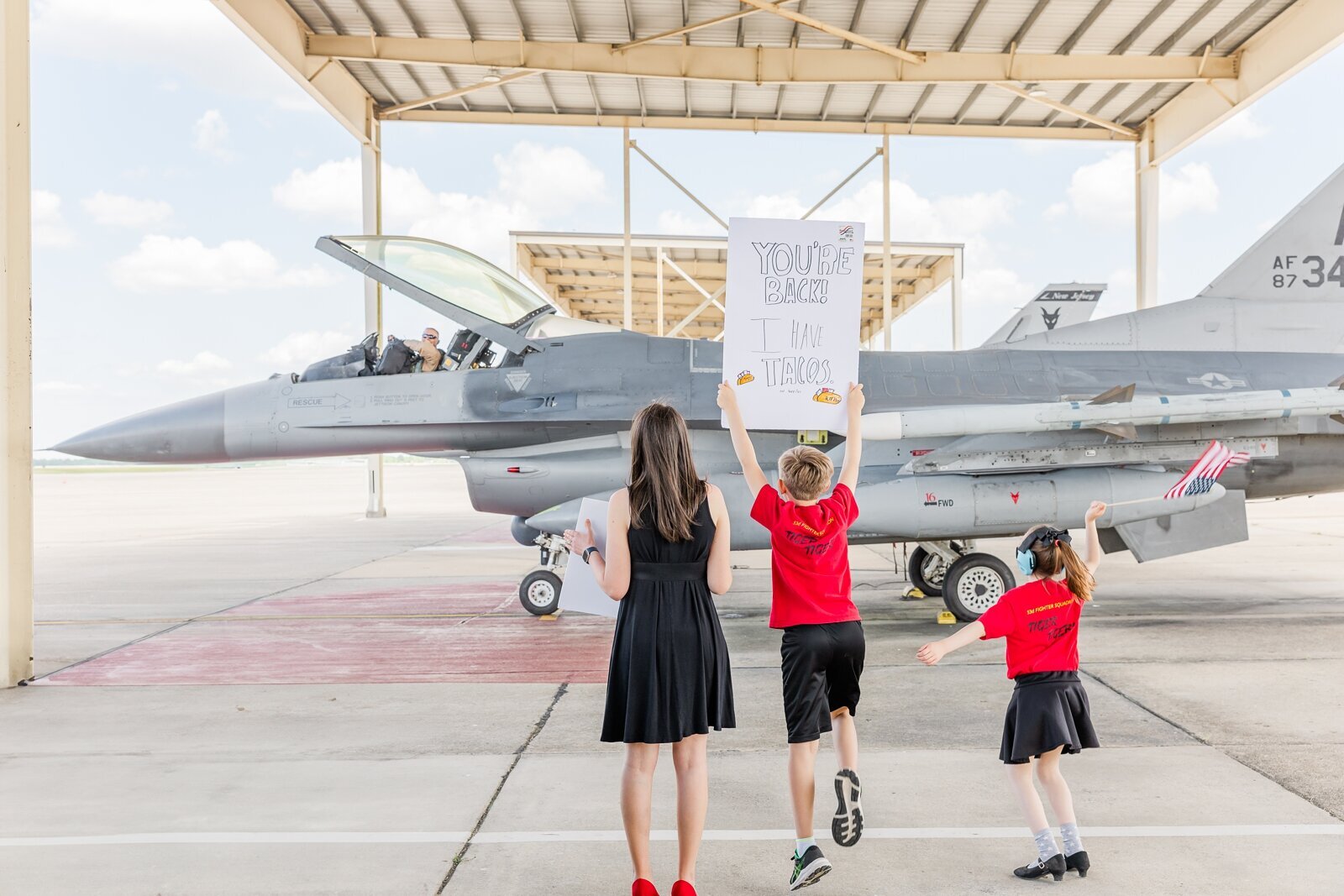 Family waving and holding signs for their dad returning from a deployment