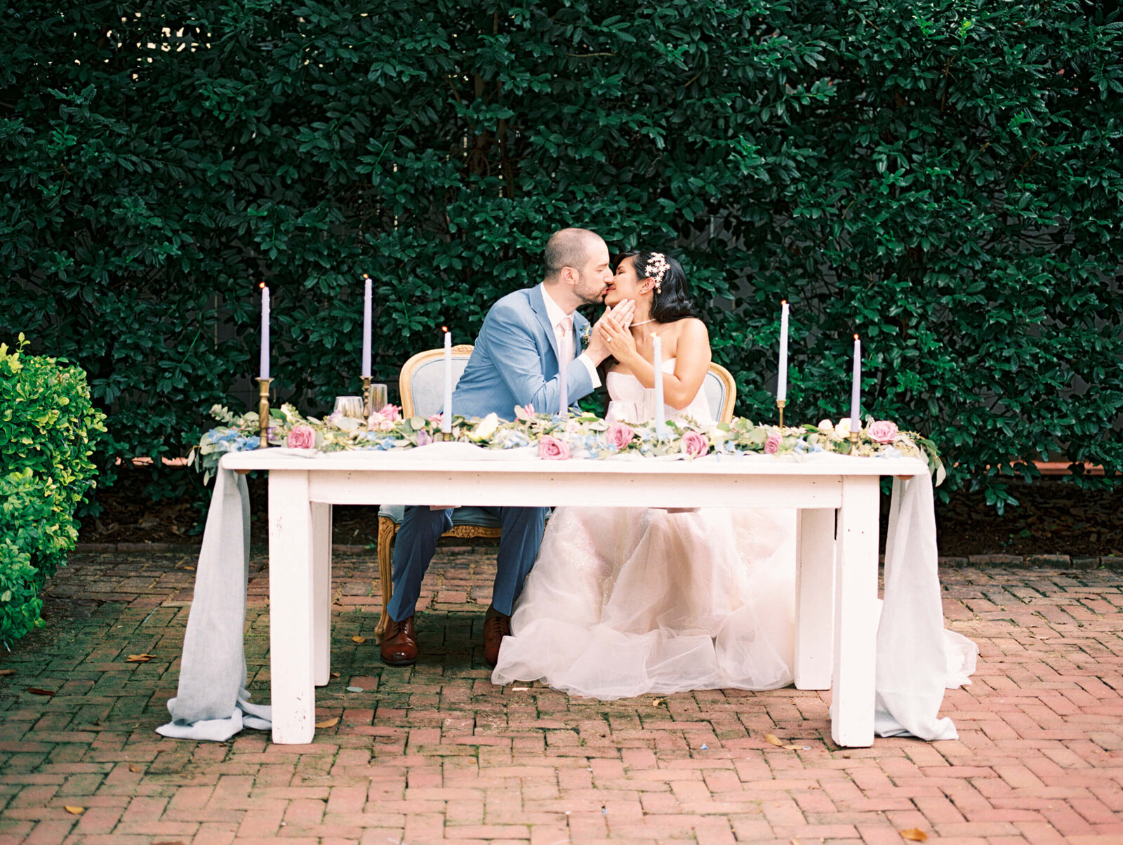 bride and groom sitting at sweetheart table and kissing