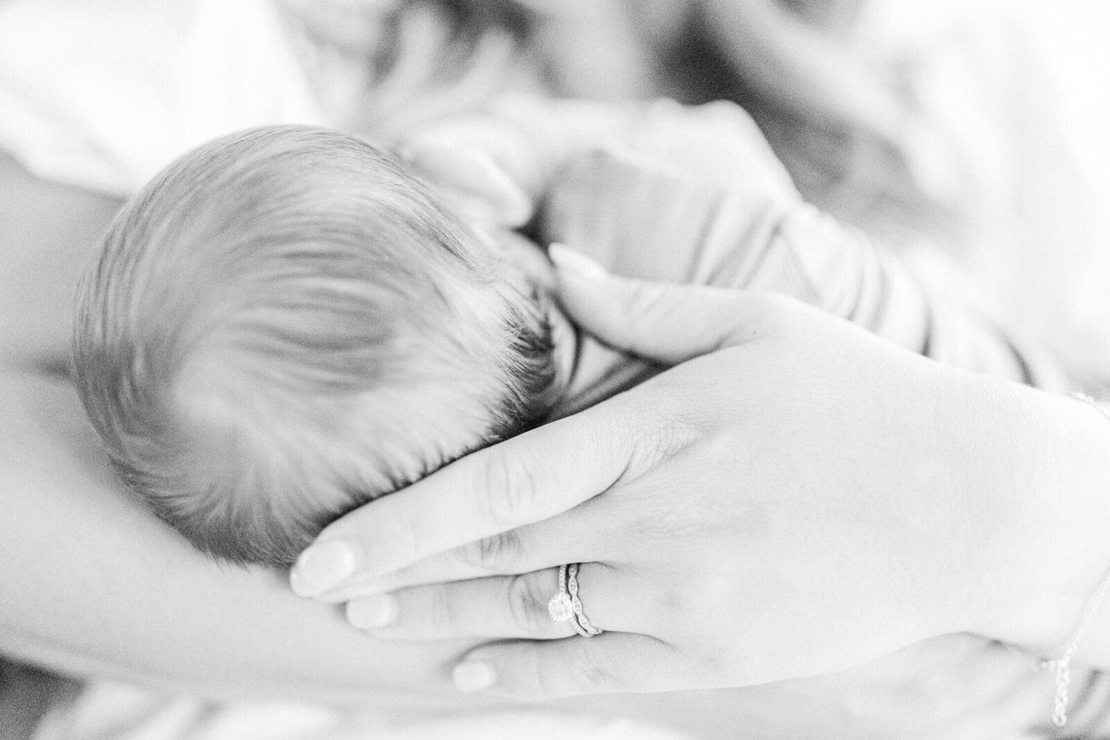 Closeup image of mother's hand supporting newborn's head while he nurses