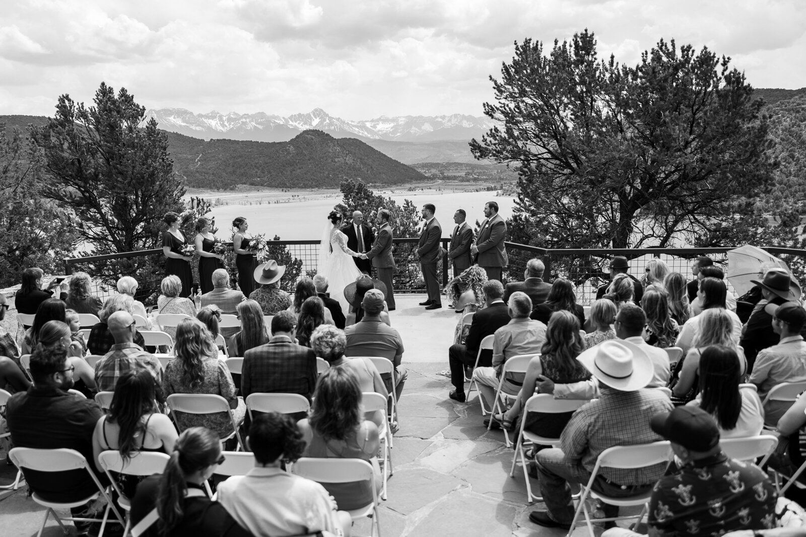 Black and white wide-angle view of a wedding ceremony at the river overlook at Ridgway State Park, surrounded by breathtaking scenery
