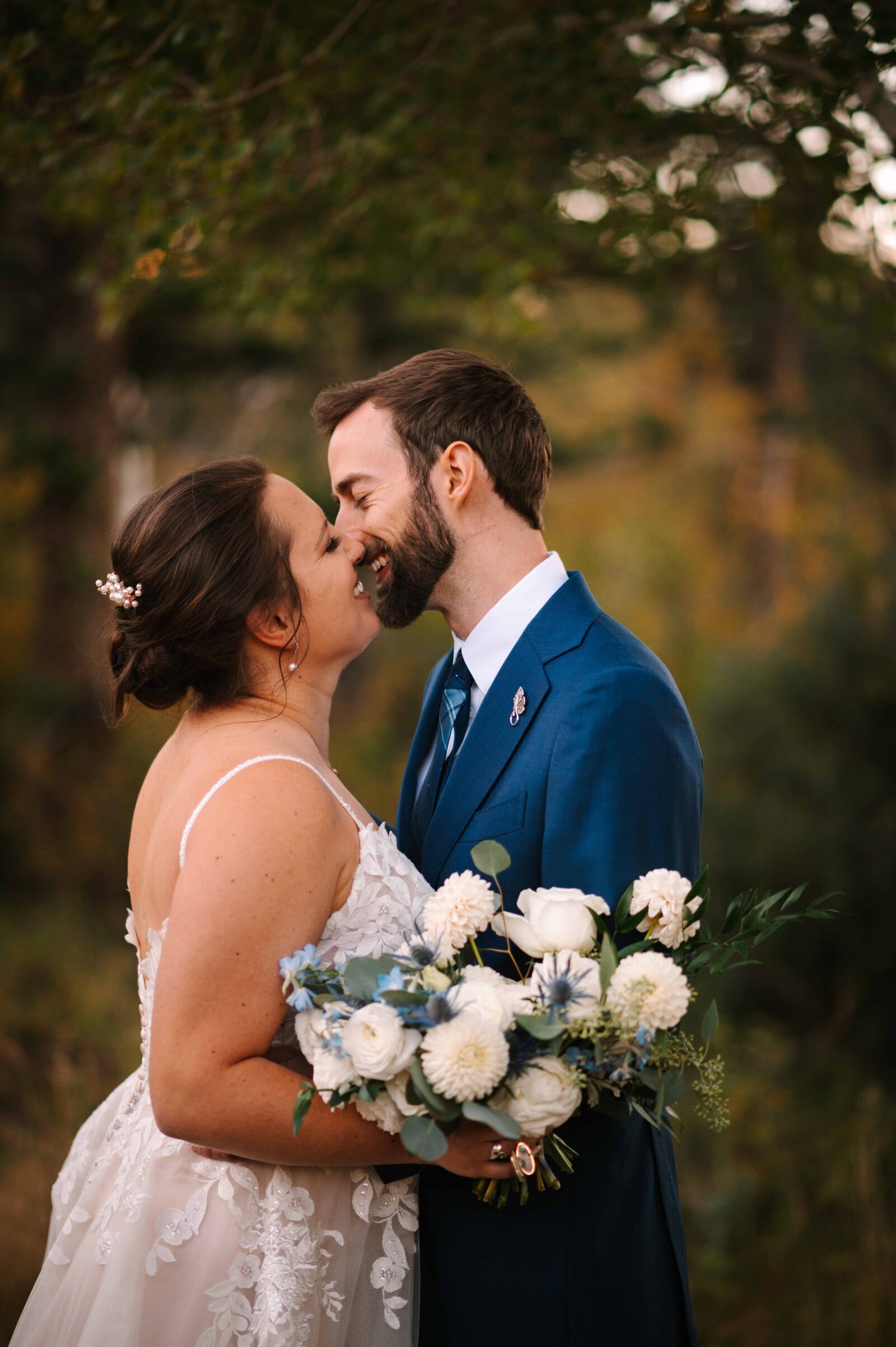 Bride and groom kissing while holding floral bouquet