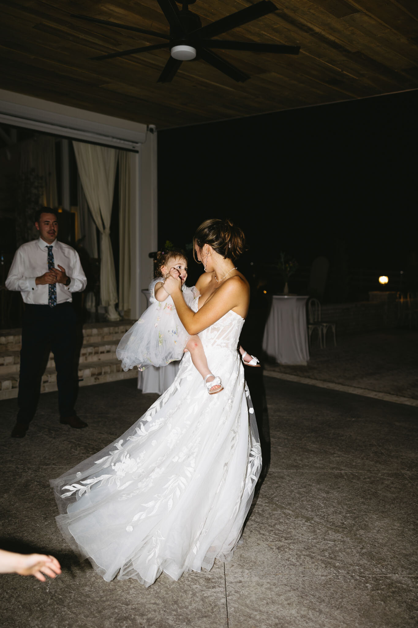 Bride carrying a baby while looking the groom