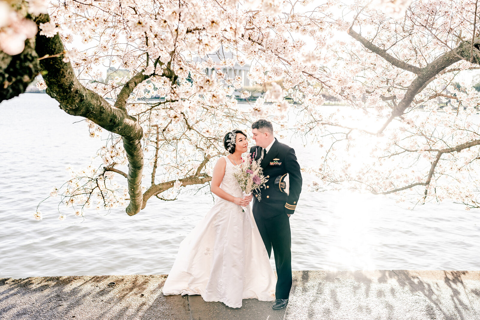 A bride and groom smile at each other underneath the trees for cherry blossom portraits in Washington DC