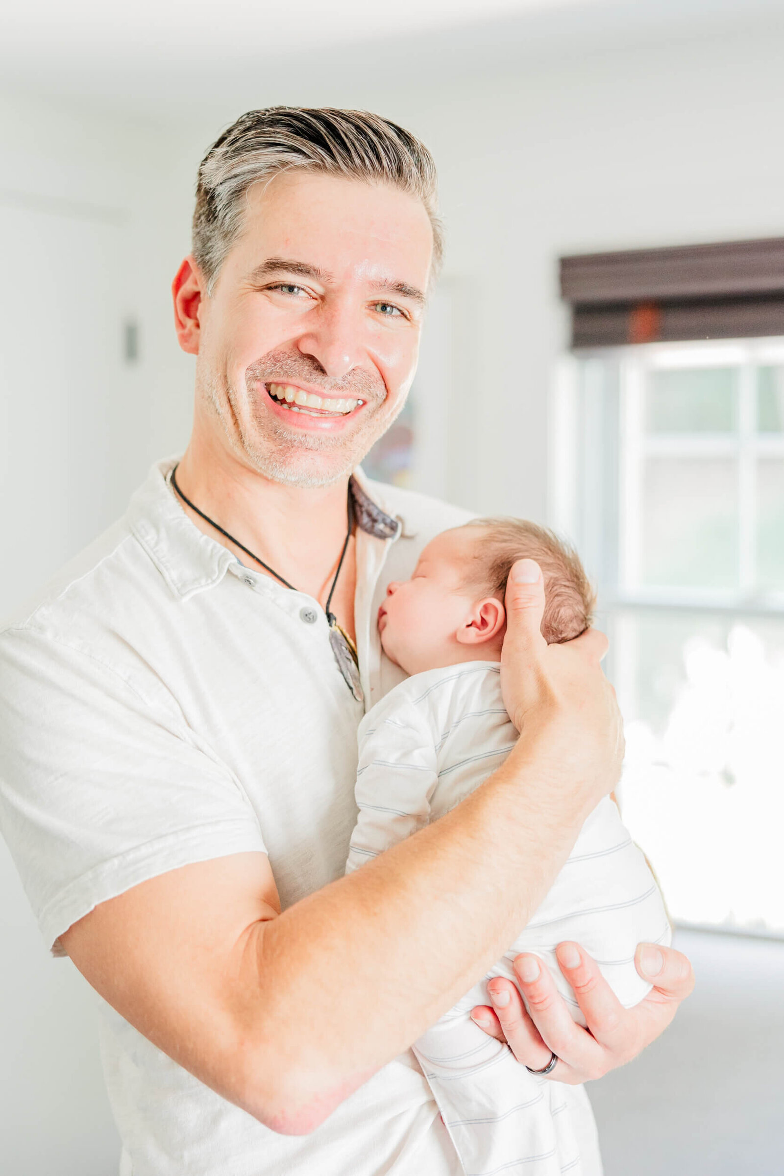 Dad smiling and holding his newborn in the nursery