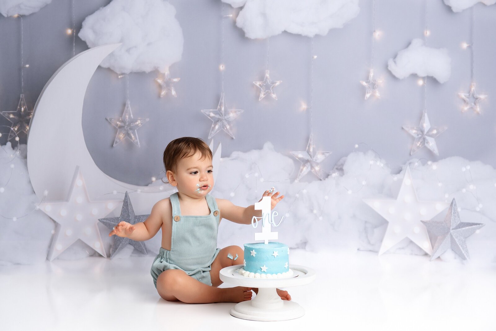 Twinkle twinkle little star cake smash photoshoot in West Palm Beach with little boy and his blue cake with a one on it.