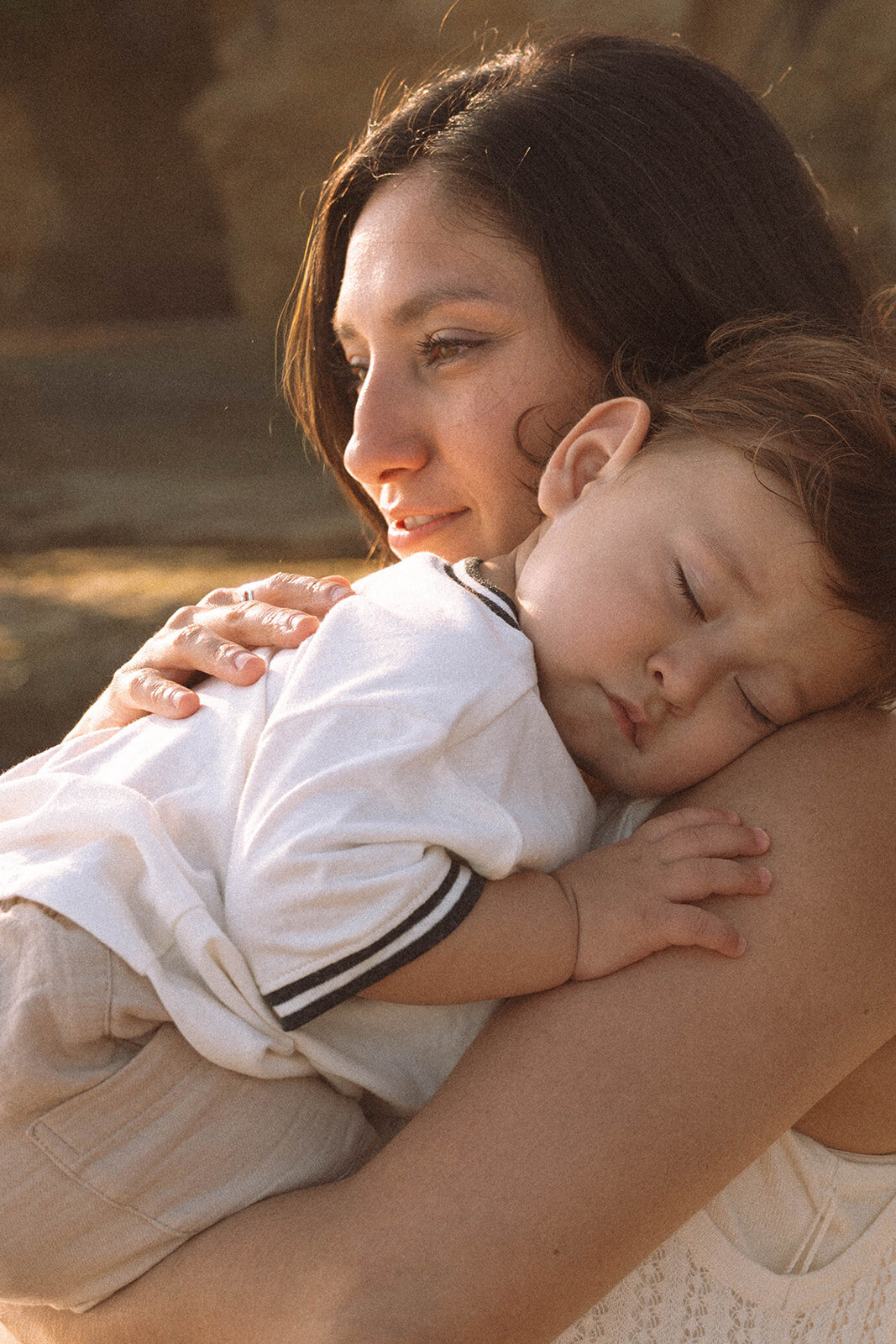 Mother hugging her sleepy baby during a candid family photography session at Shaws Cove, Laguna Beach.