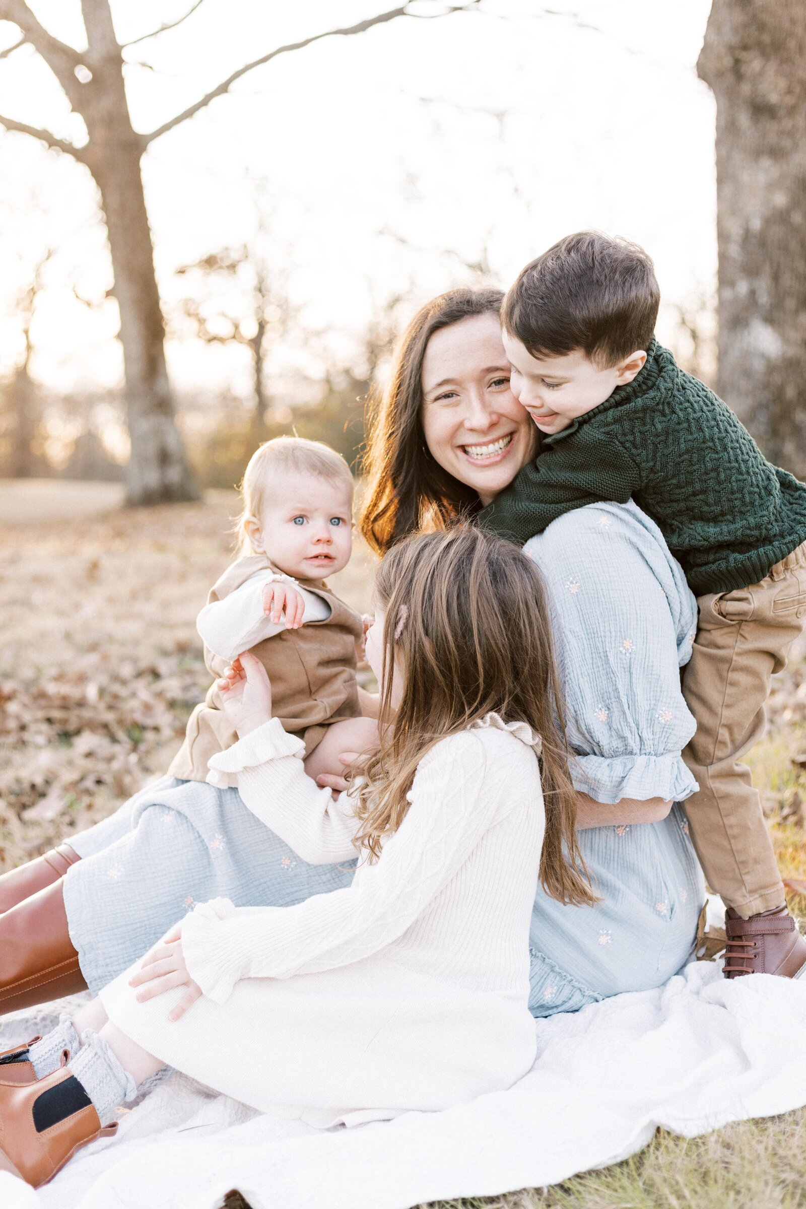 mom sitting outside with kids on her lap during peoria illinois family photos 