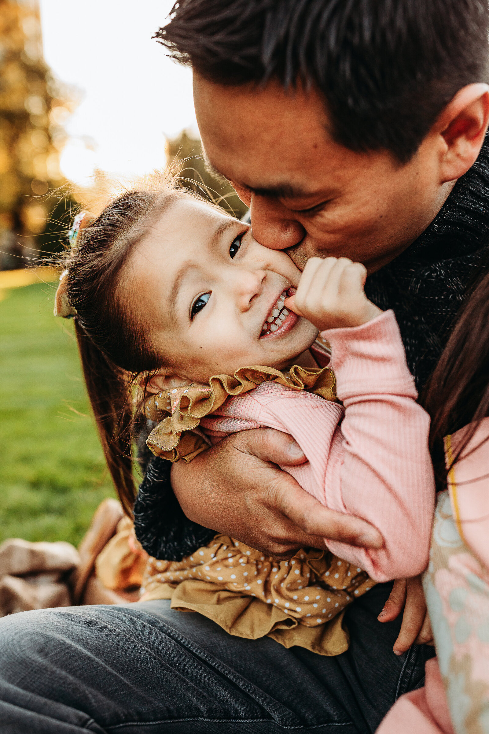 father kisses daughter on cheek at sunset in boston common