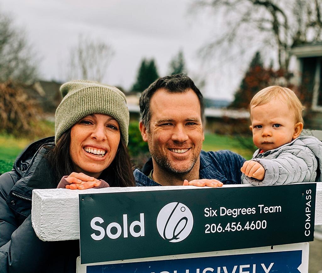 A happy family in front of a sold sign