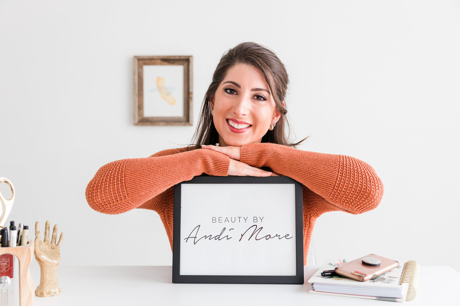 Make Up Artist Beauty By Andi More Branding Photography Female Orange Sweater Holding Business Sign at Desk