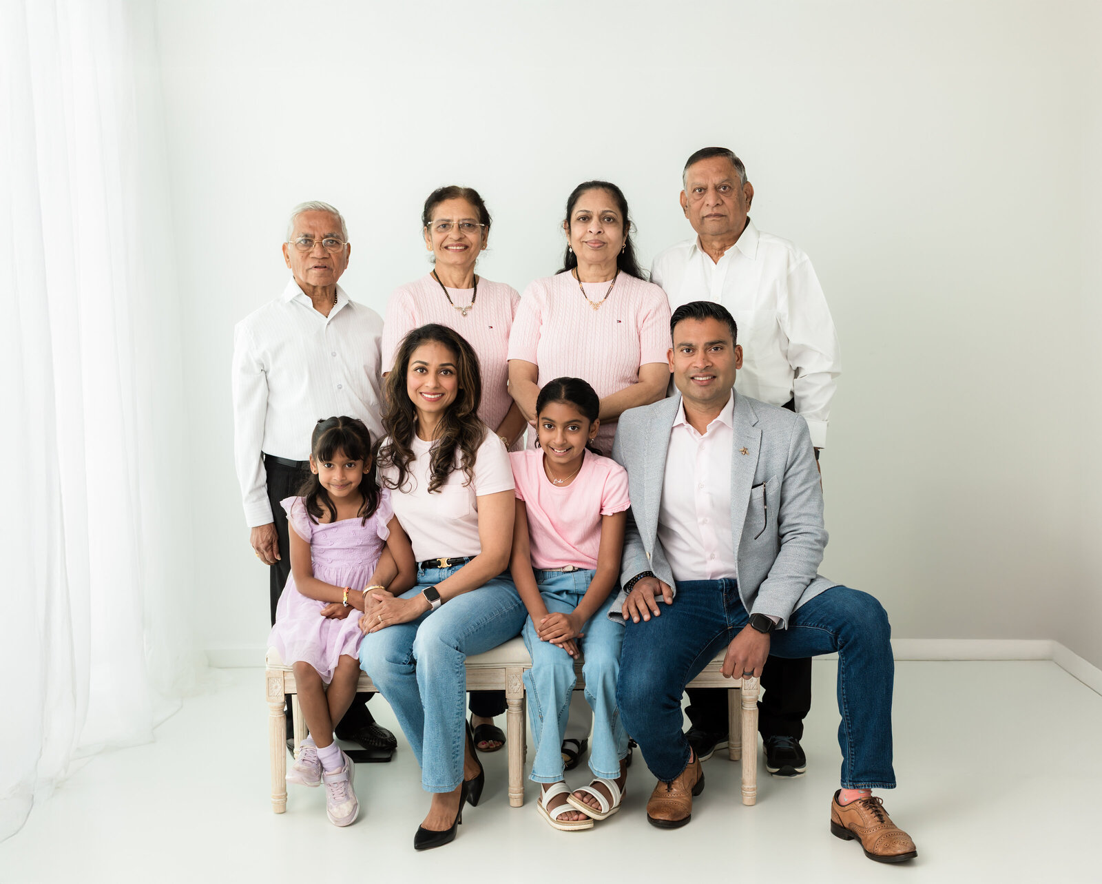 children, parents and grandparents posed for white studio portrait