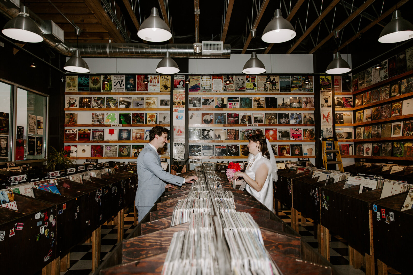 A couple sifts through vinyls at a record shop on their elopement day.