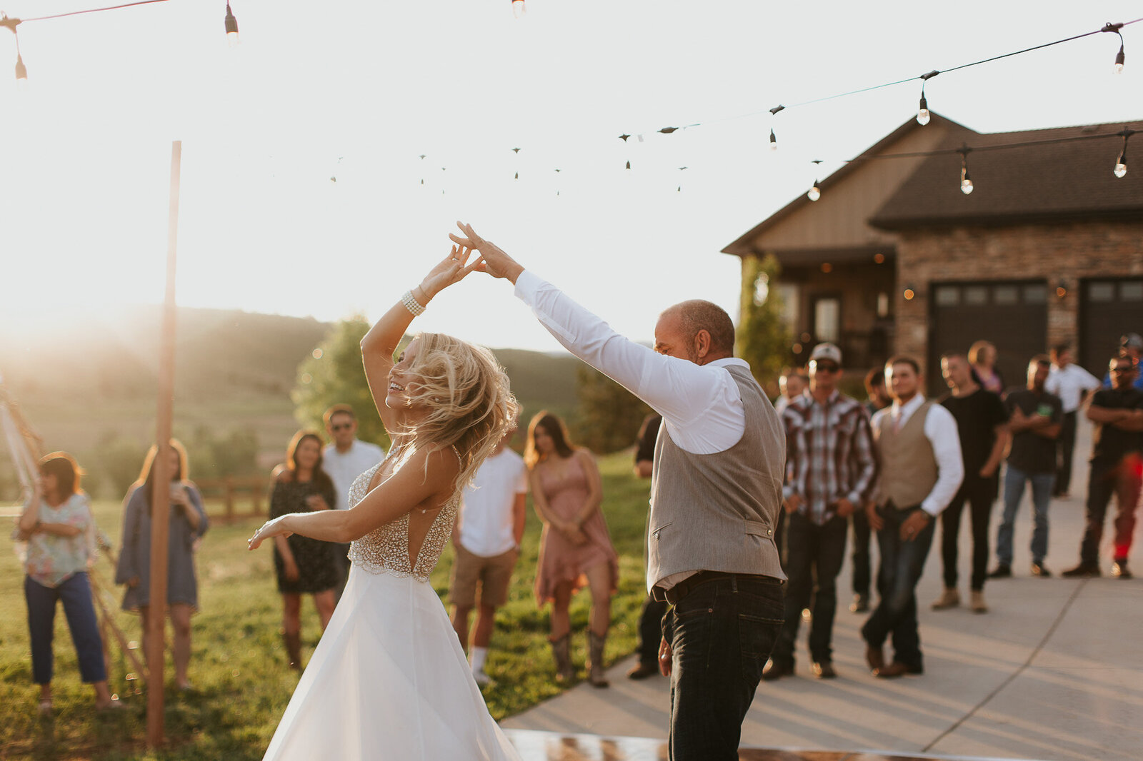 groom twirling bride on the dance floor at sunset