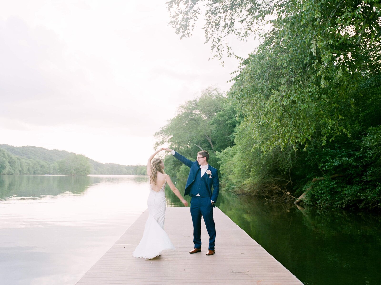 A wedded couple dance on a dock at the river for their Roswell River Landing Wedding.