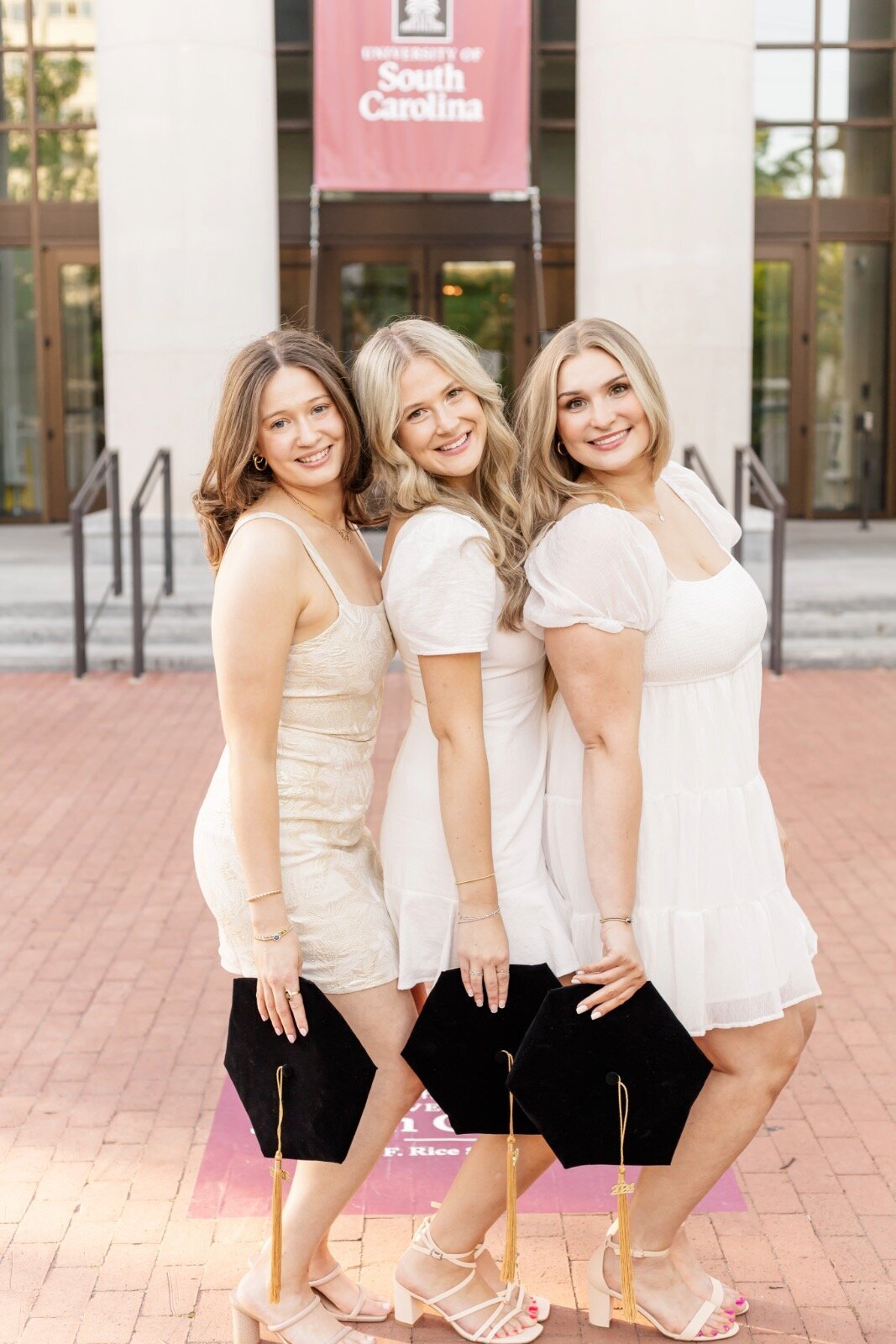three friends smiling with caps by their sides