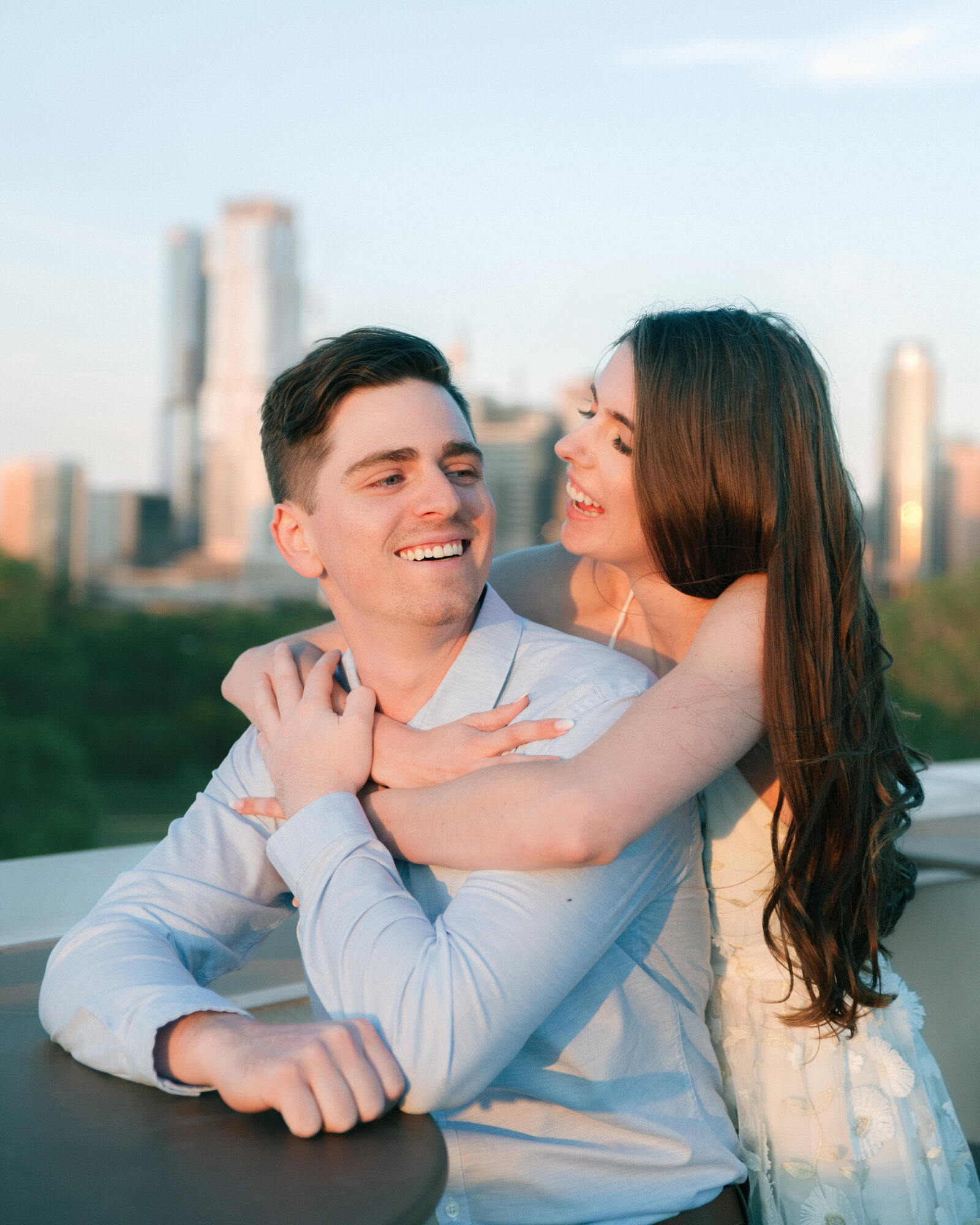 engaged couple on a rooftop with a view of the austin skyline behind them, austin engagement photo